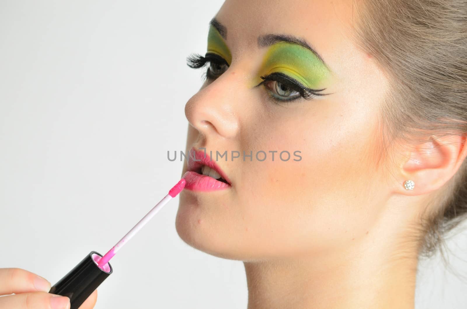 Portrait of young Polish female. Teenage girl with colorful makeup using lip gloss on her lips.