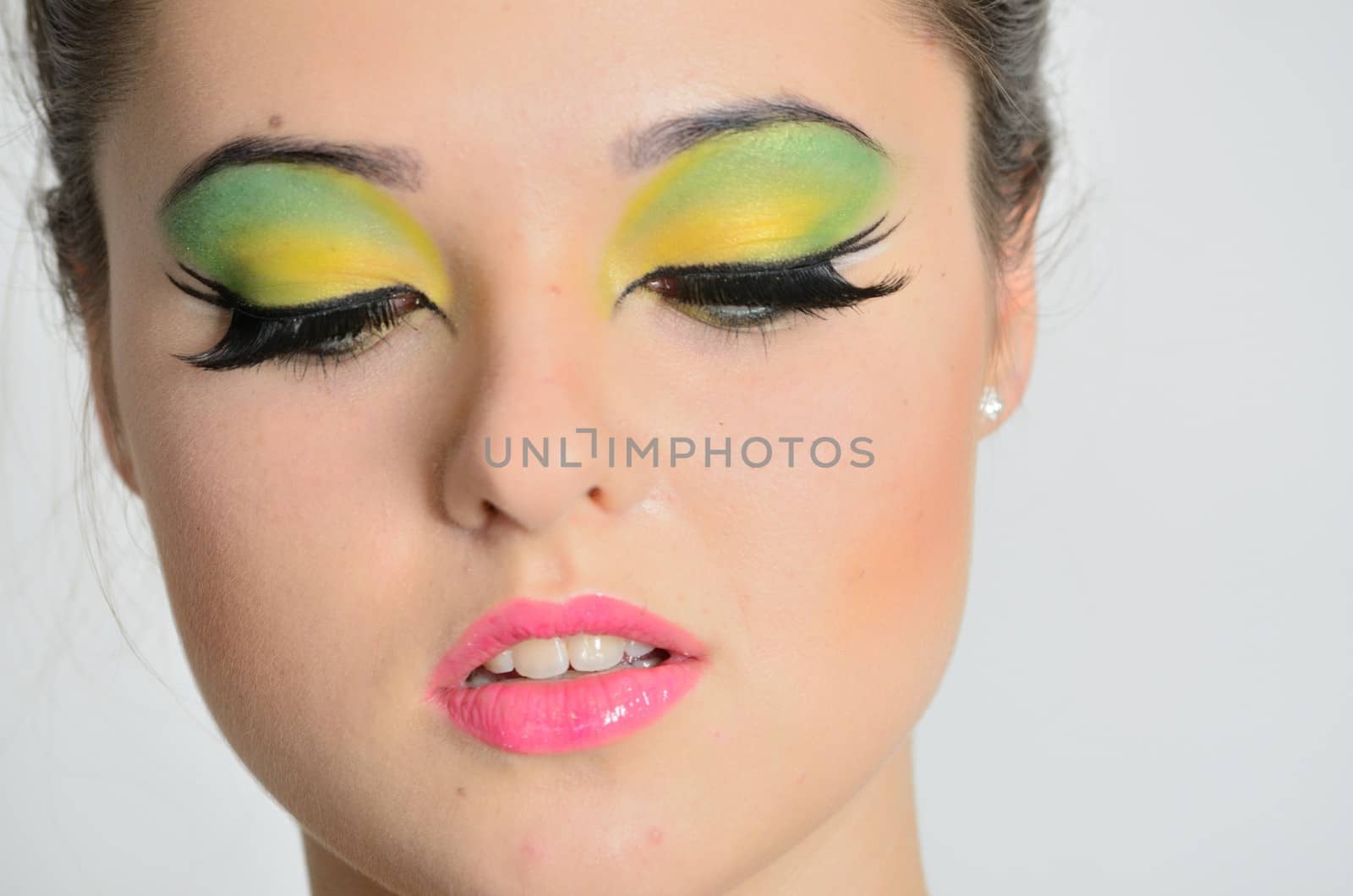 Young female model with colorful makeup. Face closeup portrait photo of teenager. 