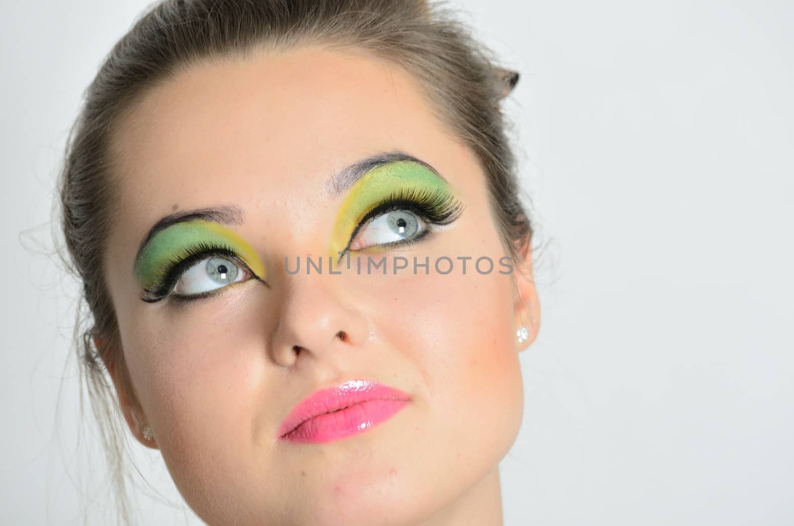 Cute teenage girl with colorful makeup with gentle smile. Female model with her eyes up.