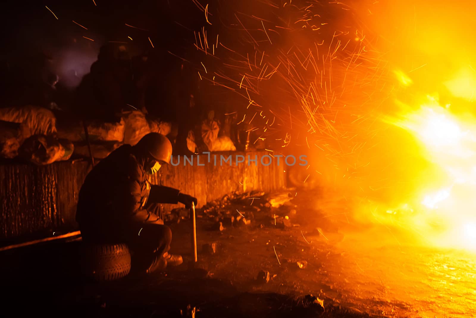KIEV, UKRAINE - January 24, 2014: Mass anti-government protests in the center of the Ukrainian capital Kiev. Member of the Popular Resistance basking near the fire  on Hrushevskoho St.
