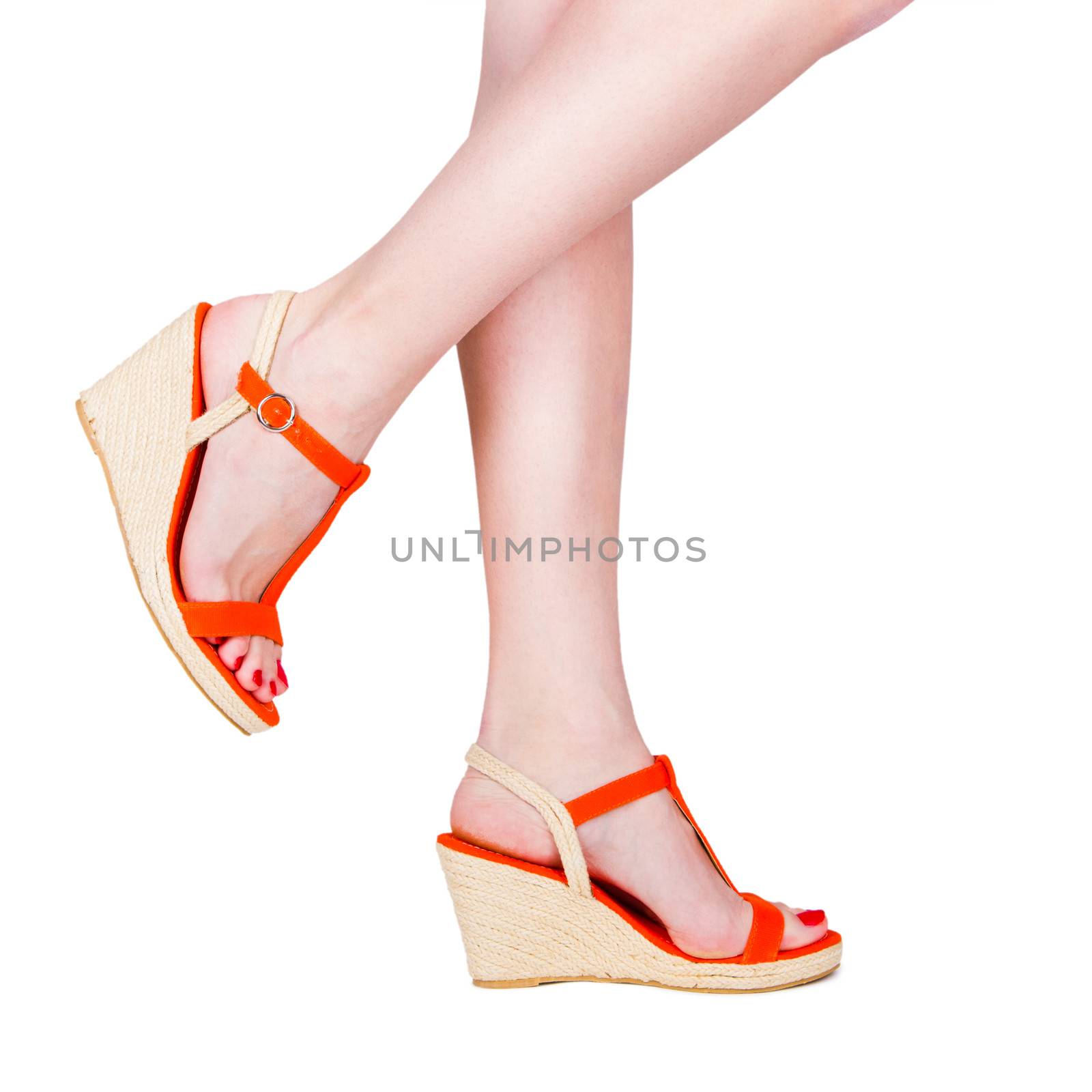 Woman legs wearing a pair of sandals, isolated on white