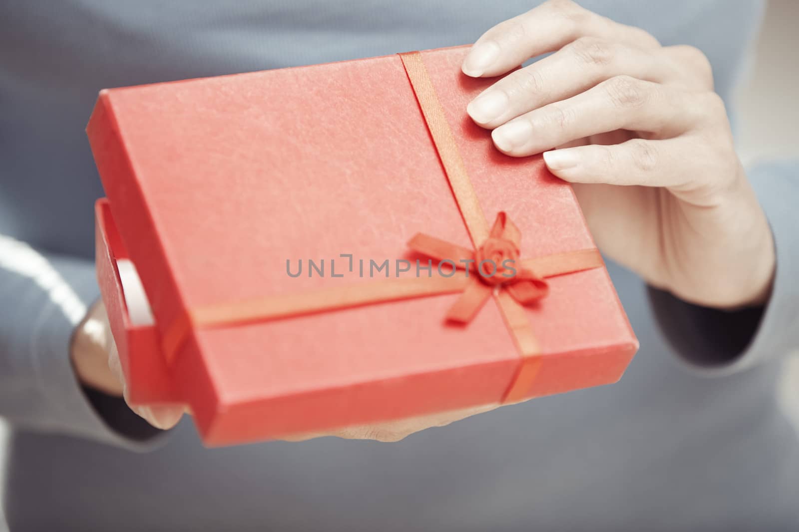 Hands of woman opening red gift box