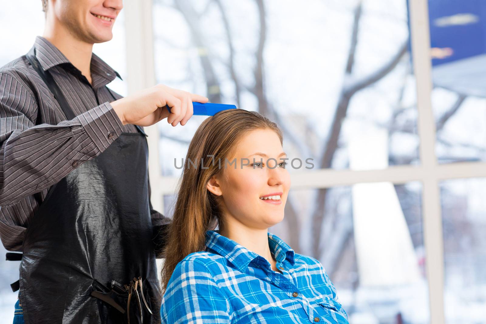 male hairdresser puts woman's hair in a hairdressing salon