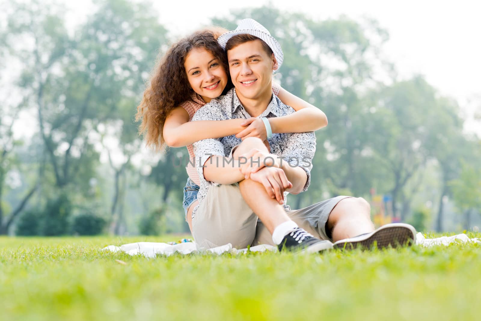 romantic couple lying on the grass in the summer park, spending time with loved ones