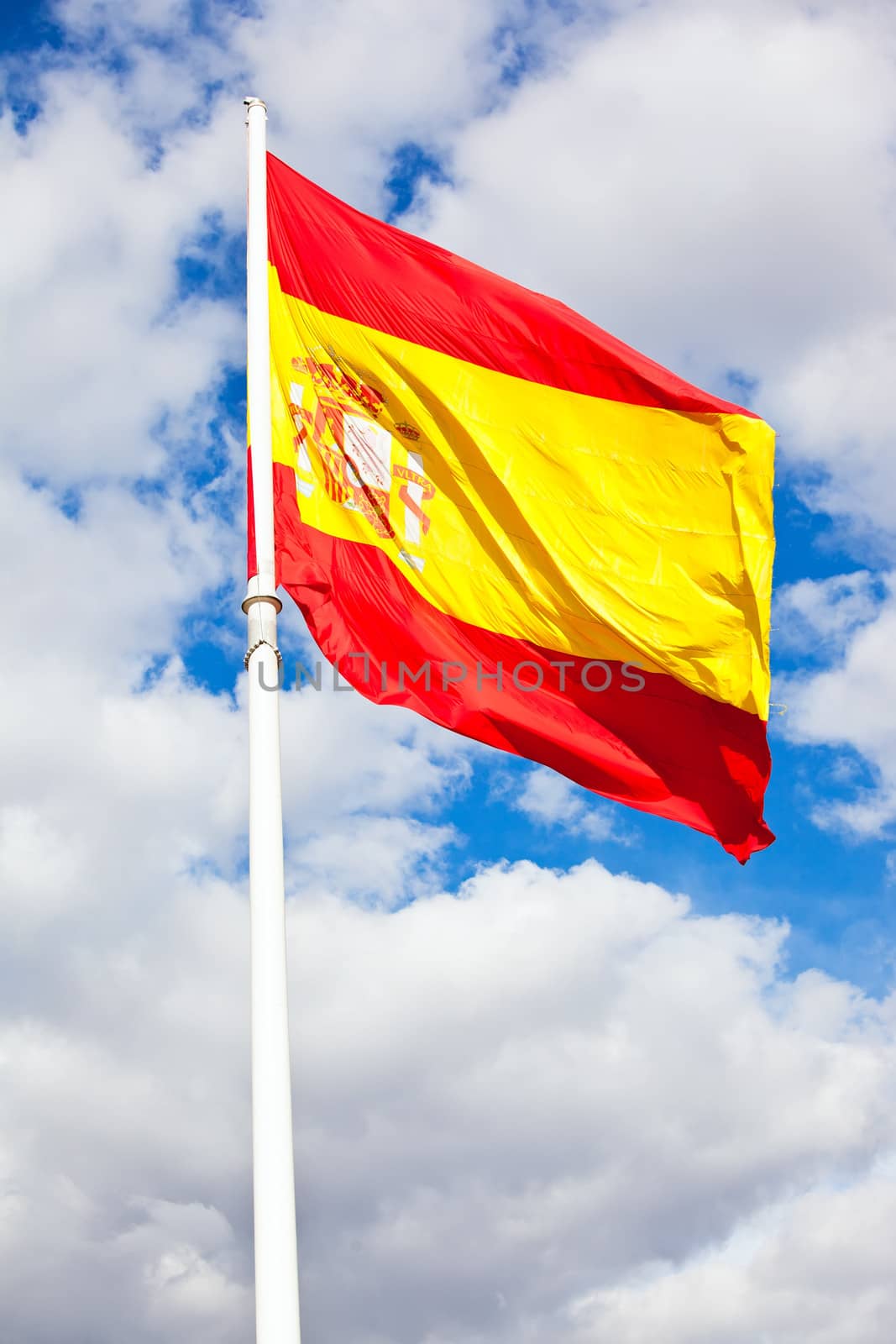 Flag of Spain over blue sky moving in wind