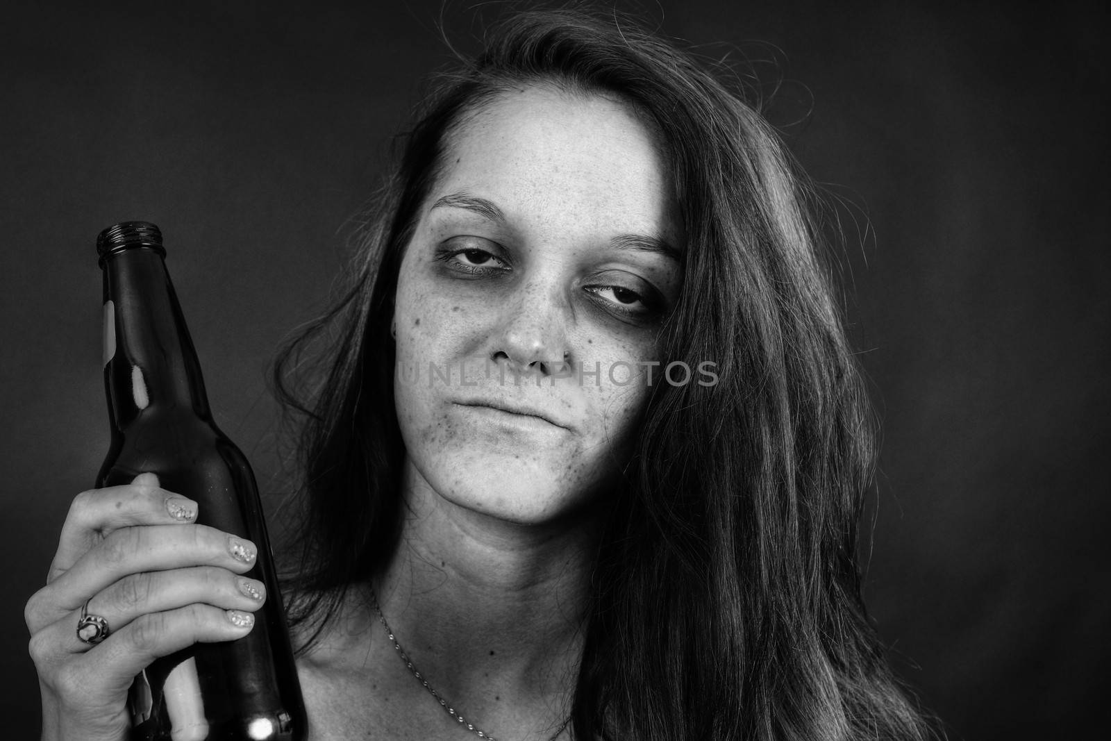 Dramatic black and white portrait of a young woman addict with beer, junkie, alcohol or drug addiction.