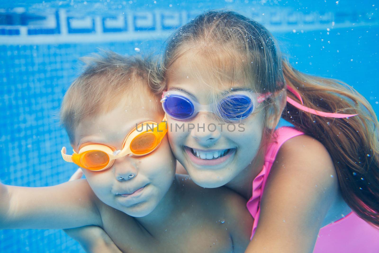 Close-up underwater portrait of the two cute smiling kids
