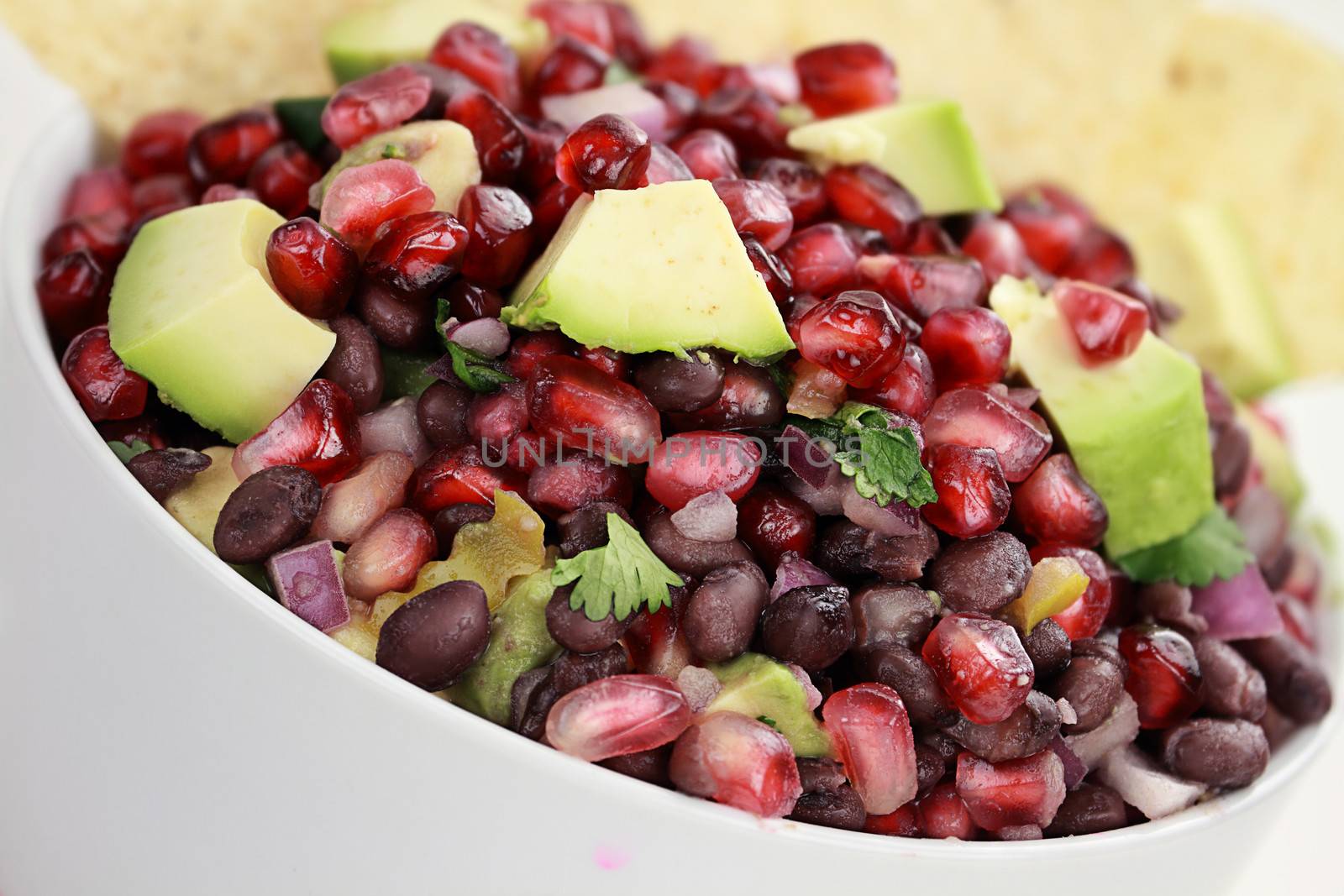 A healthy relish or salsa with pomegranate, avocado, red onions, black beans and cilantro served with corn chips. 