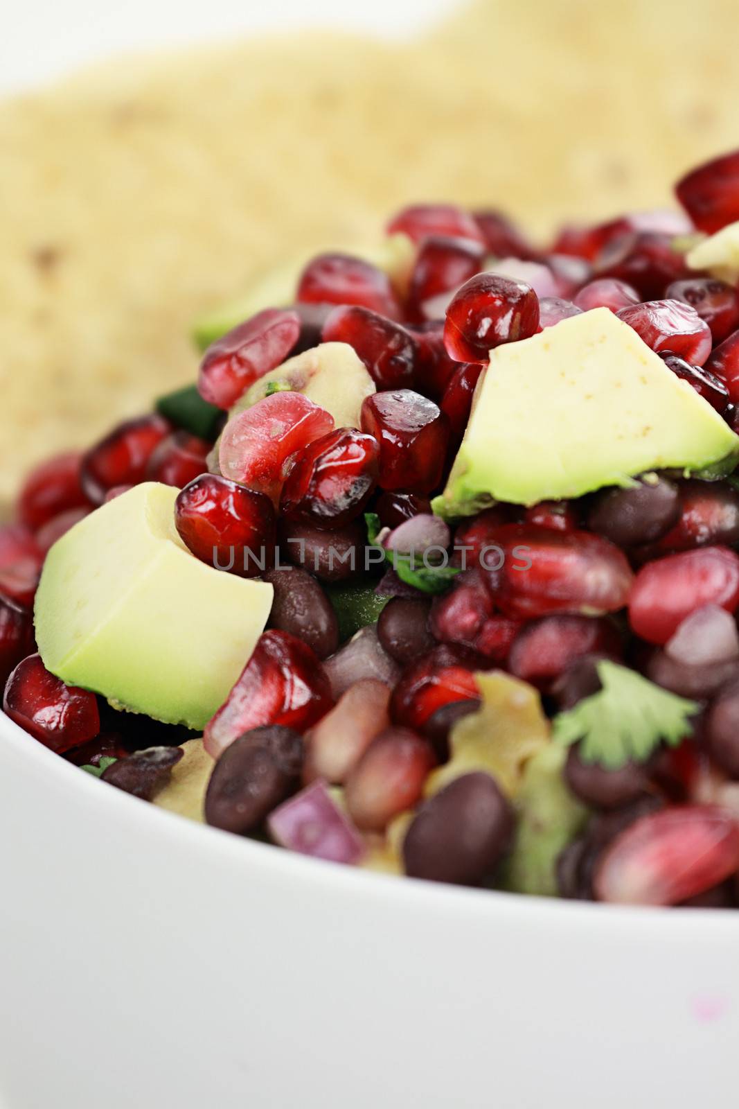 A healthy relish or salsa with pomegranate, avocado, red onions, black beans and cilantro served with corn chips. 