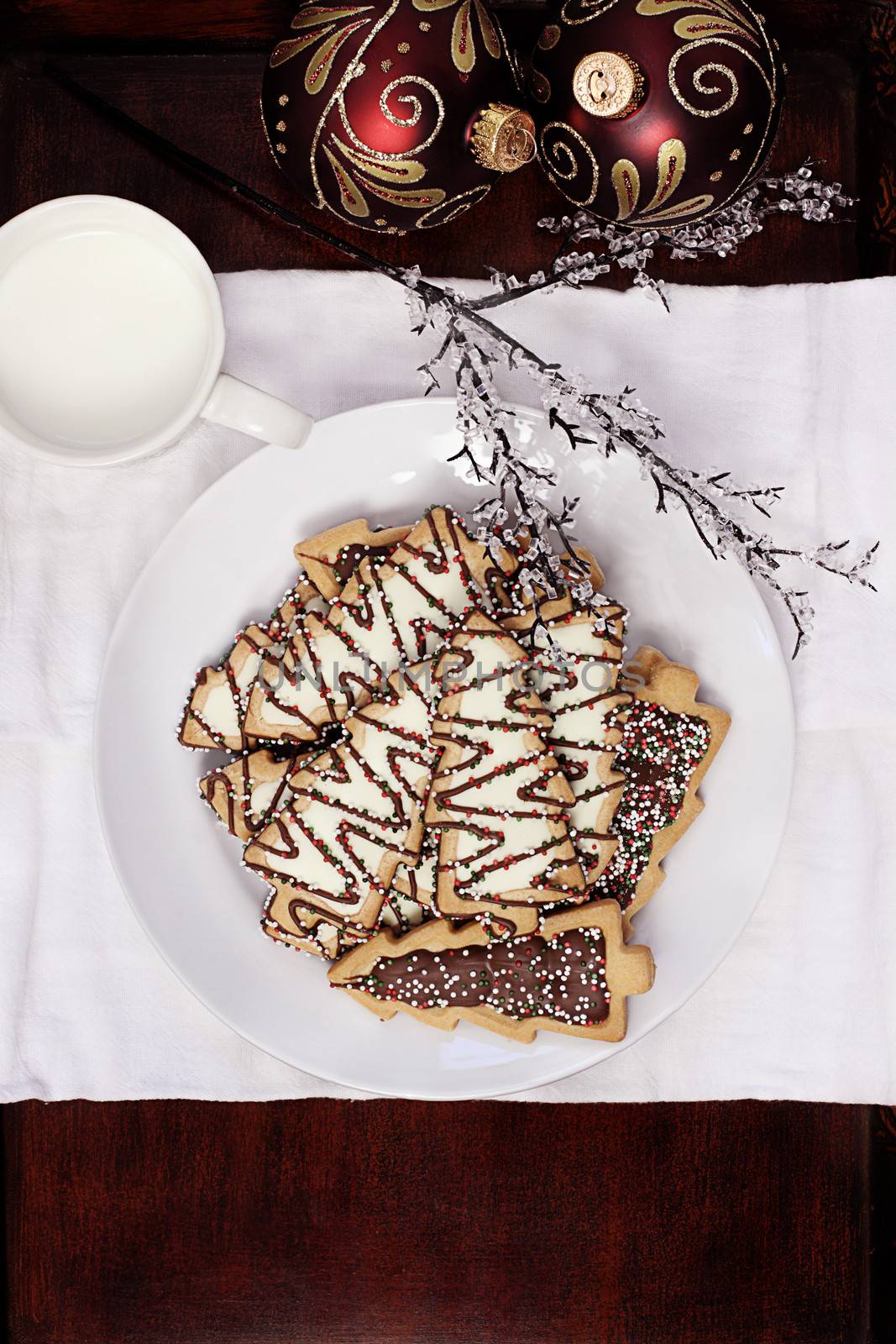 Plate of Christmas trees with cup of milk and beautiful ornaments in the background. 