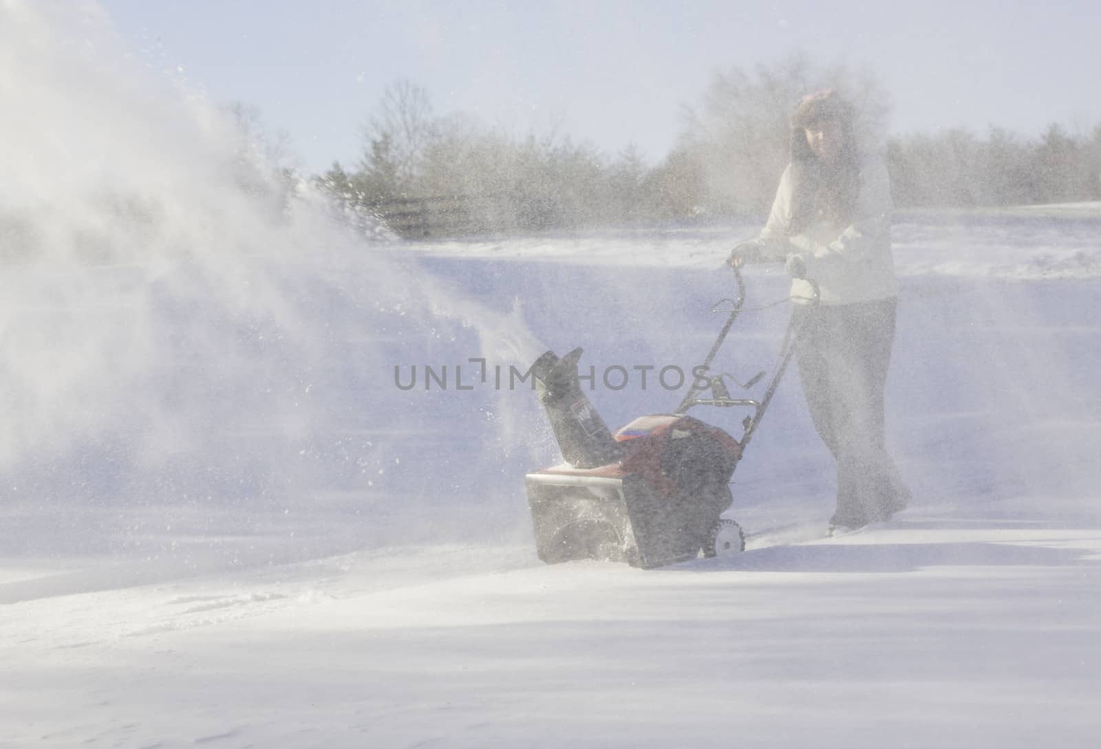 Young woman clearing drive with snowblower by steheap