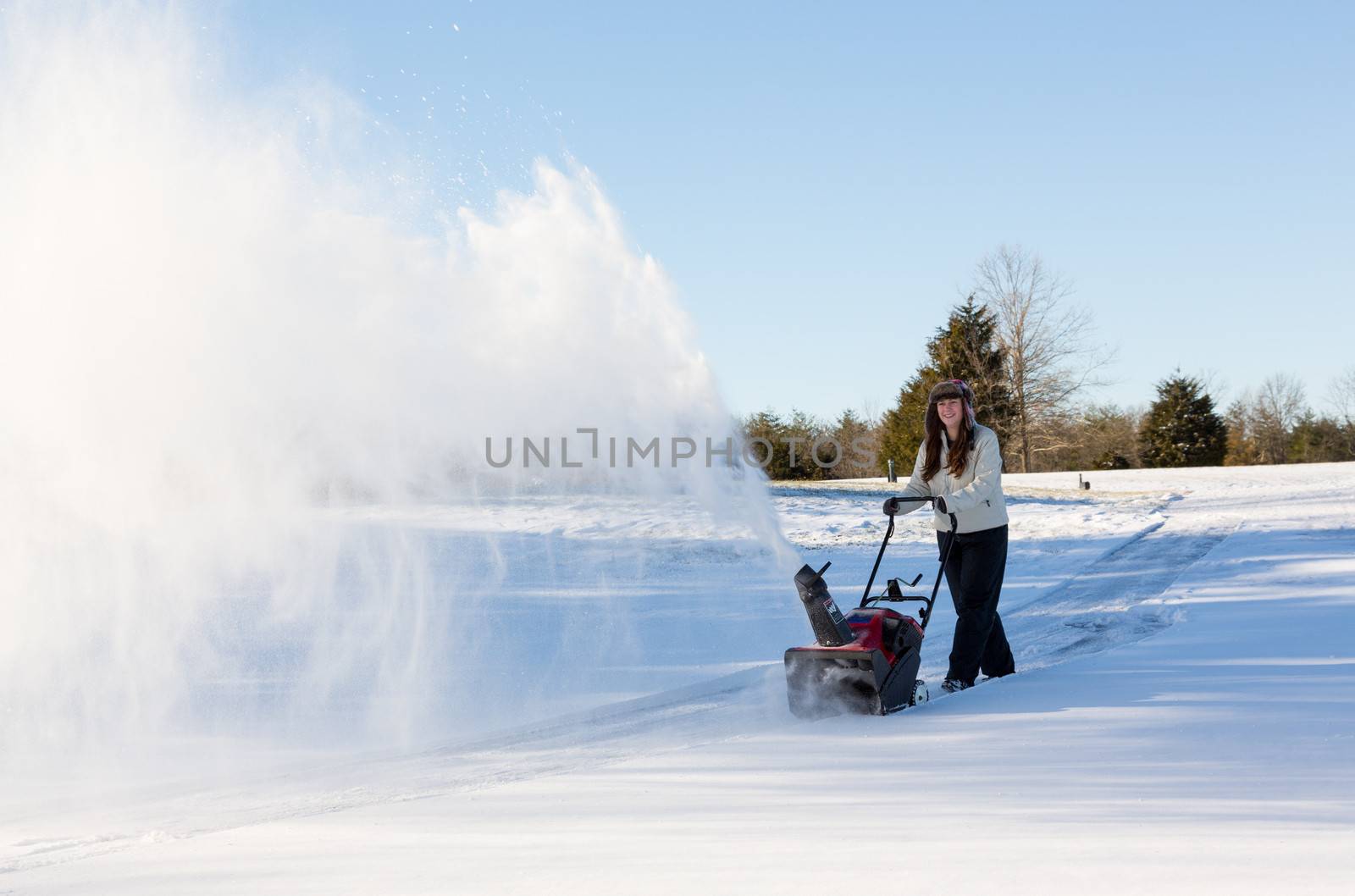 Young woman clearing drive with snowblower by steheap