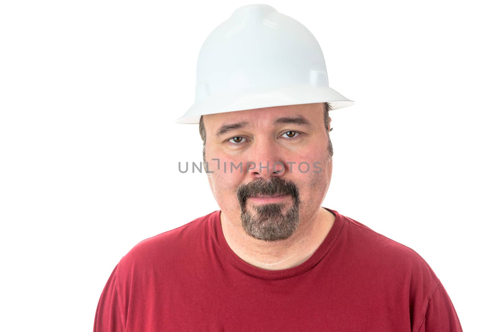 Workman or technician with a goatee beard wearing a white hardhat standing looking directly at the camera, isolated on white