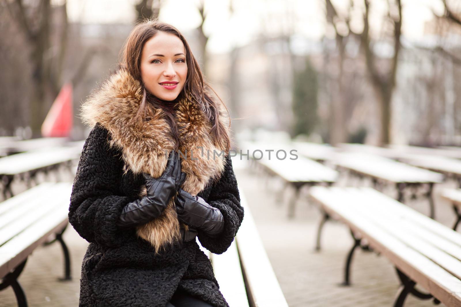 Young woman sitting on the bench in winter park