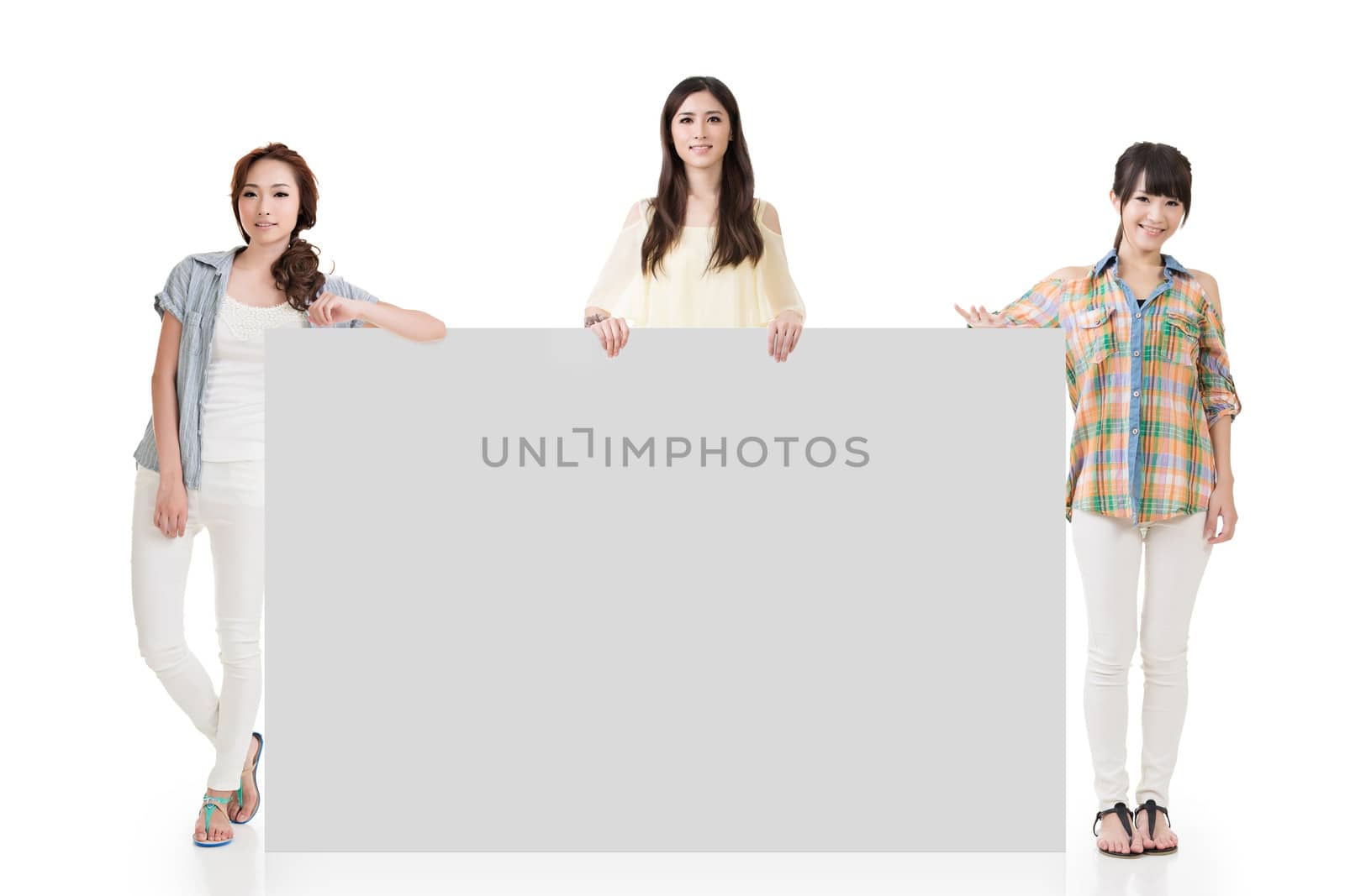 Three pretty women showing an empty board with copyspace for advertising.