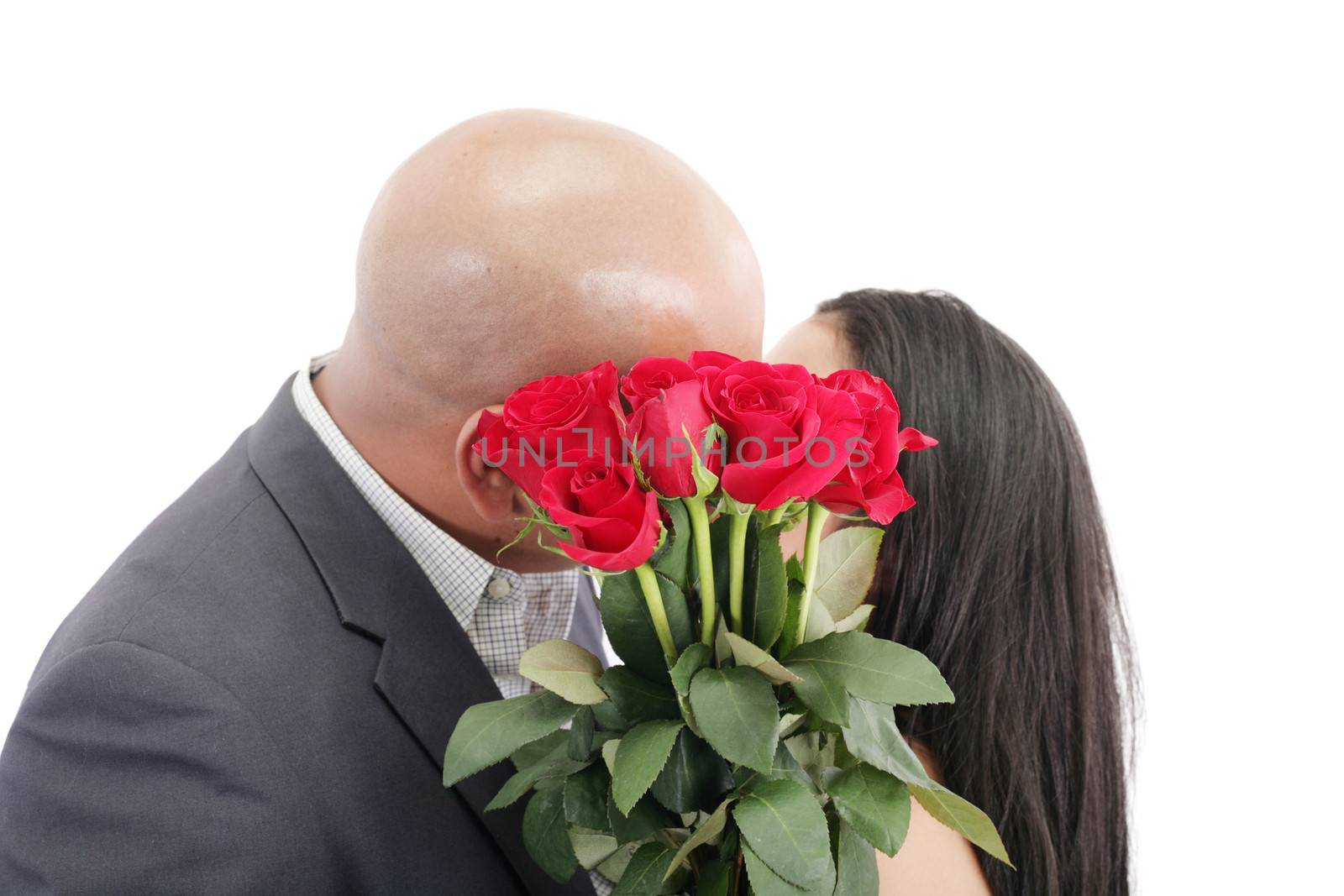 Two young dates kissing behind a bouquet of red roses by dacasdo