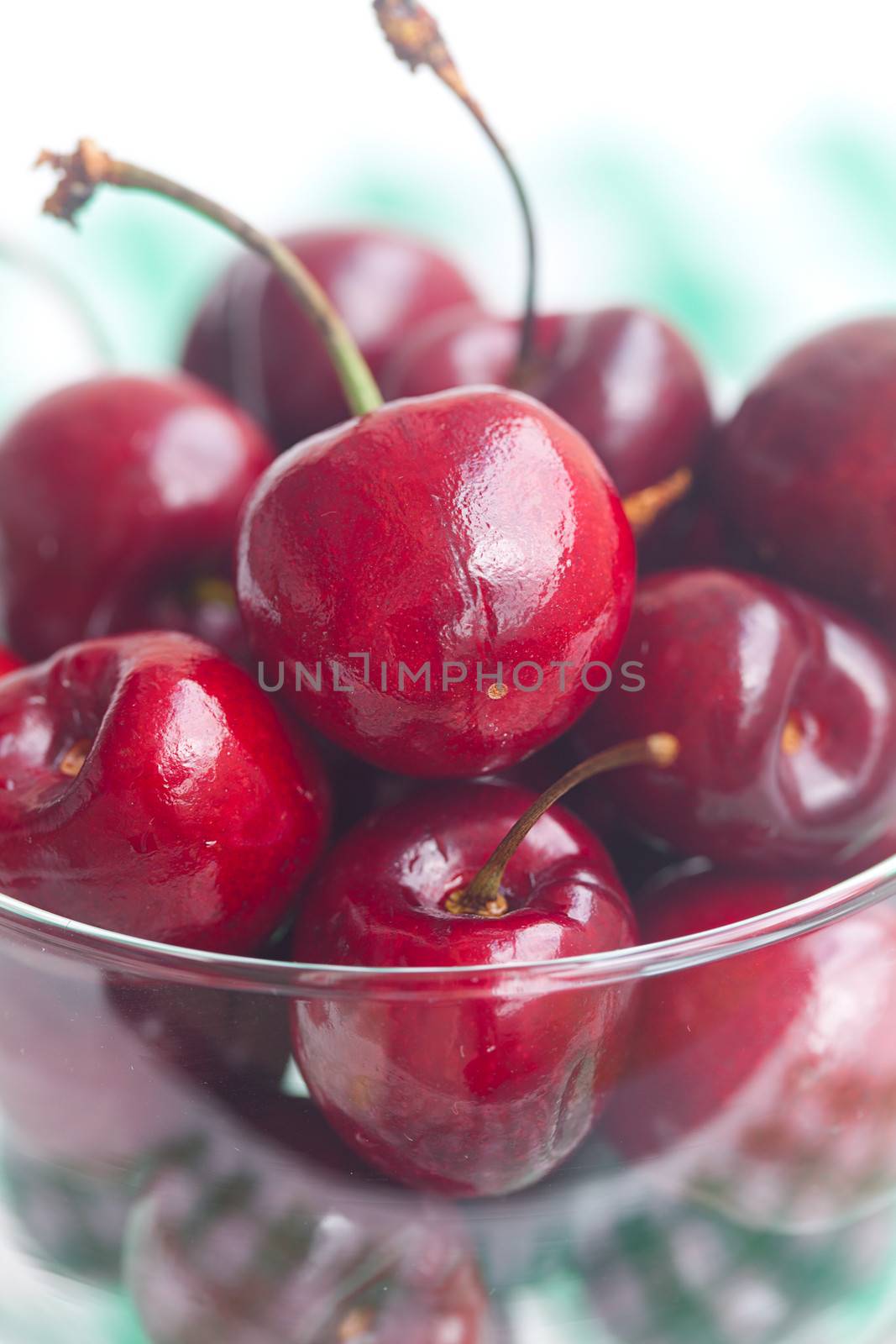 Cherries in a glass bowl on checkered fabric by jannyjus