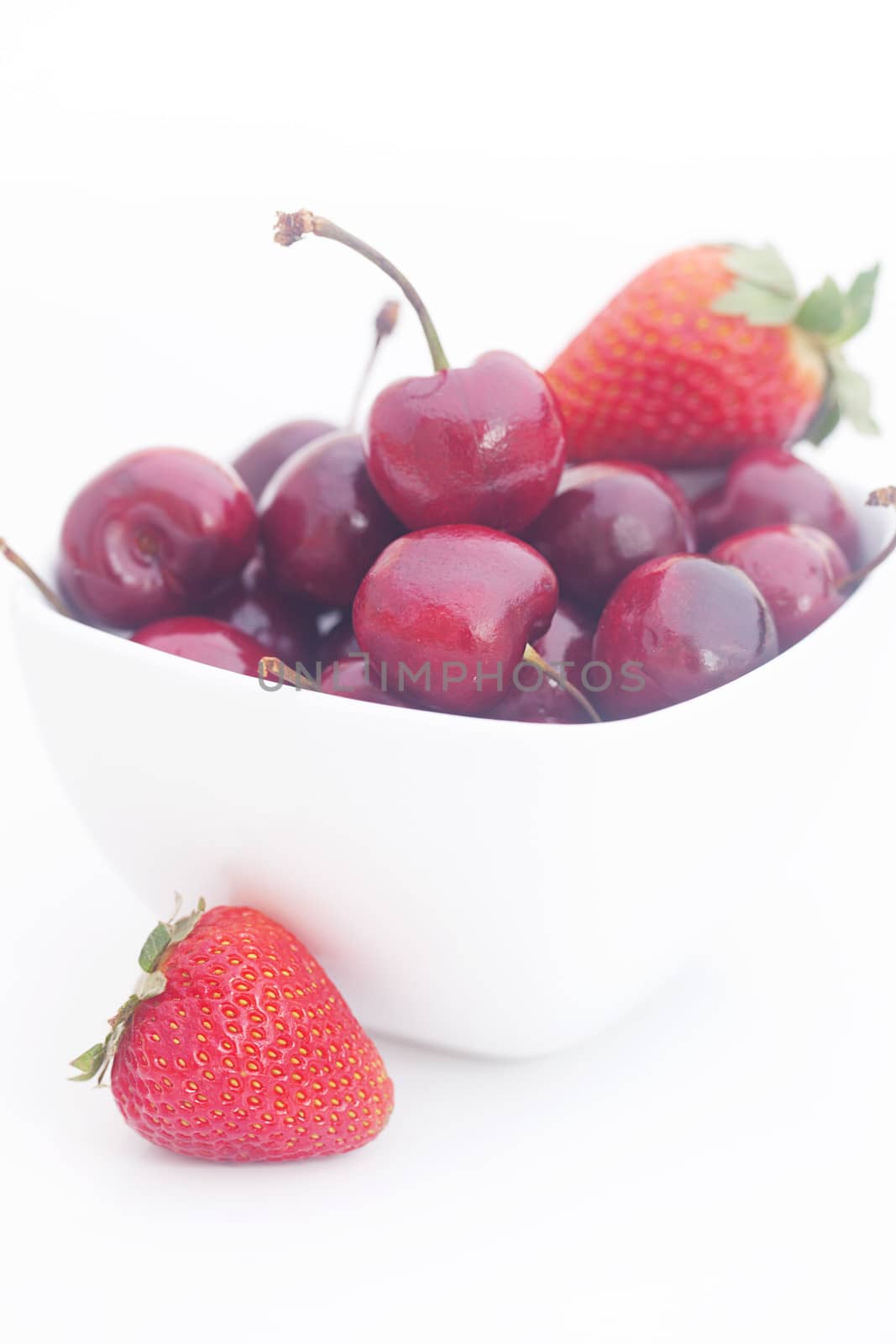 Cherries and strawberry in a ceramic bowl isolated on white