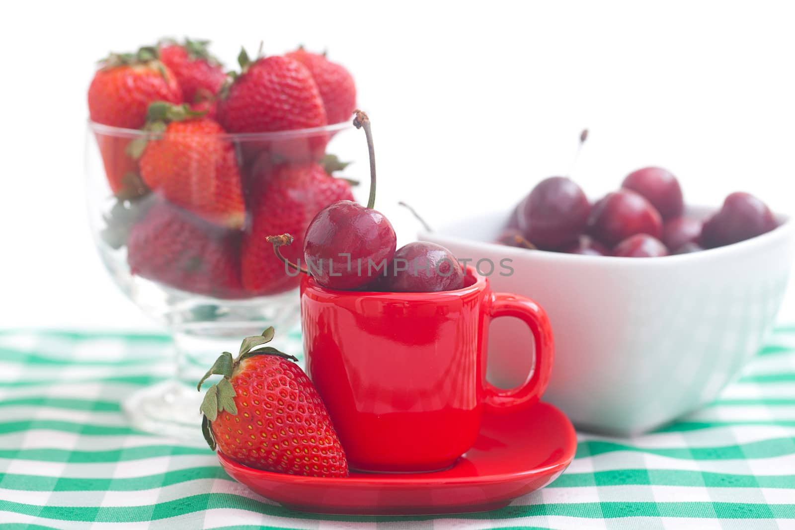 Cherries and strawberry in a ceramic and glass bowl on checkered by jannyjus