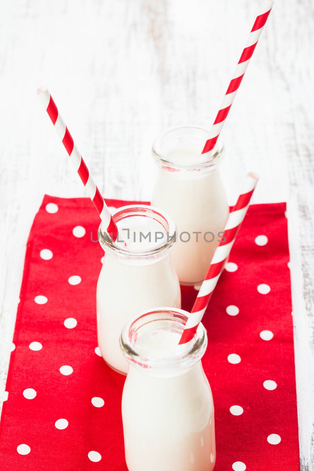 Milk in bottles with paper straws for children on the red polka dot napkin