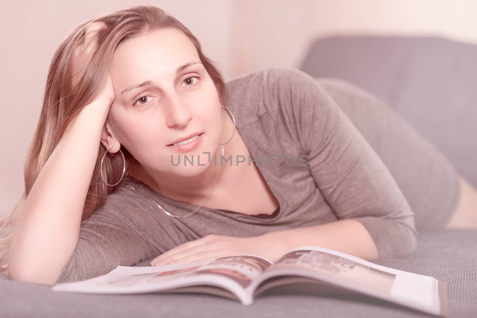 Young woman on the bed reading a magazine