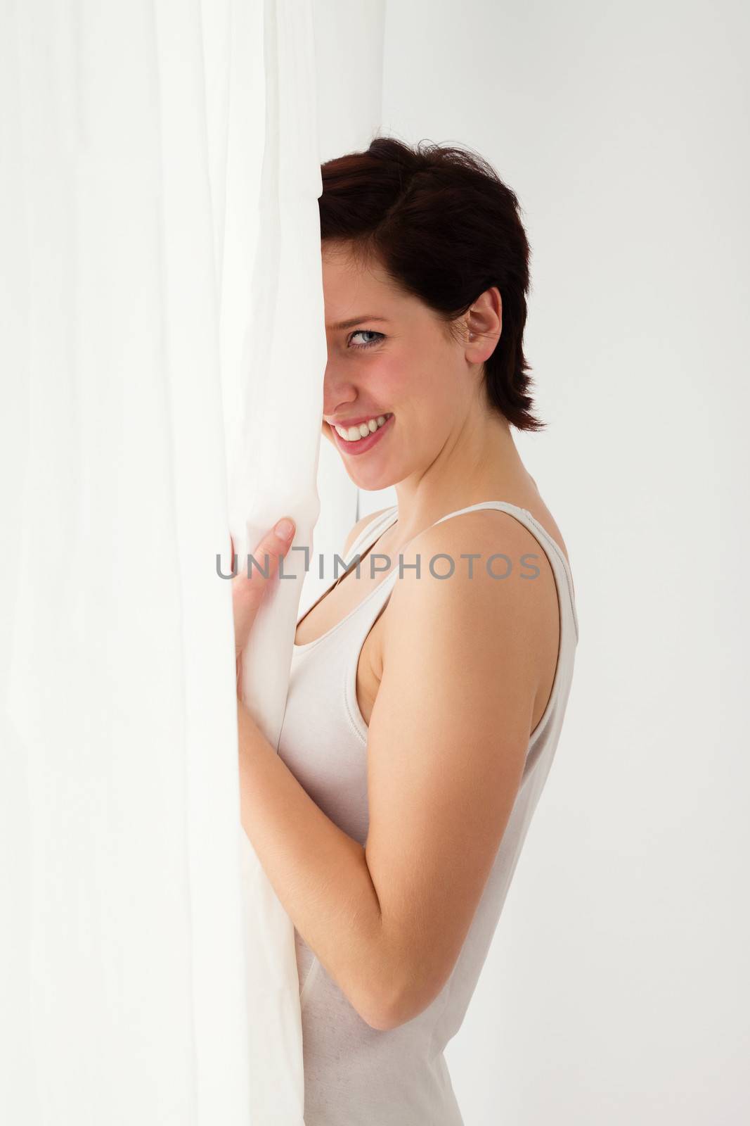 happy cute woman hiding slightly behind a curtain