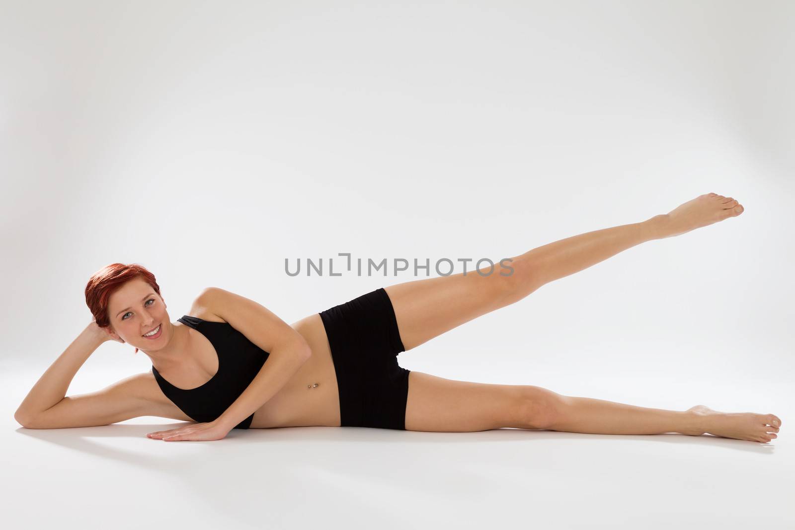 young happy redhead fitness woman exercising with her legs