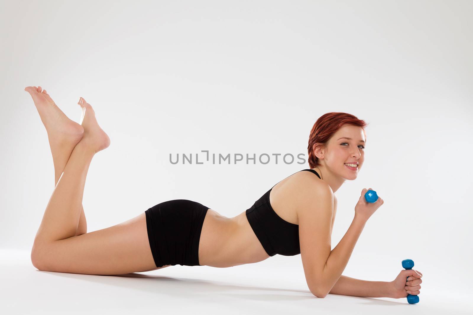 happy fitness woman exercising elbow pushups with dumbbells