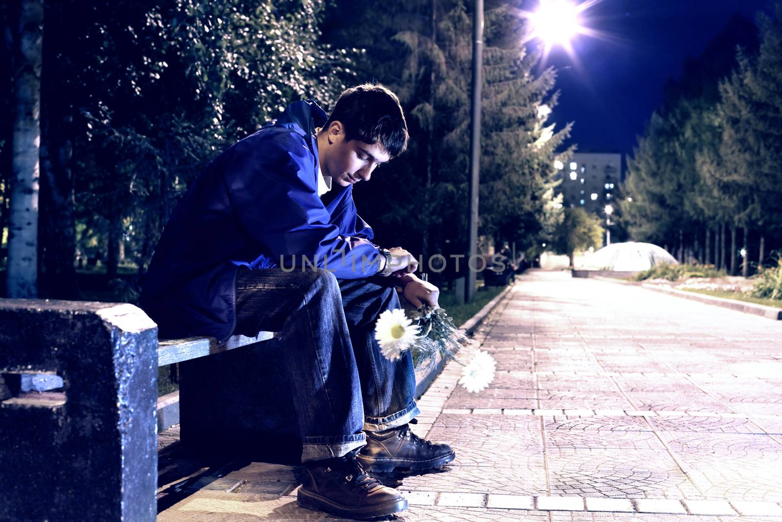 Toned Photo of Teenager with flowers sitting in the night park