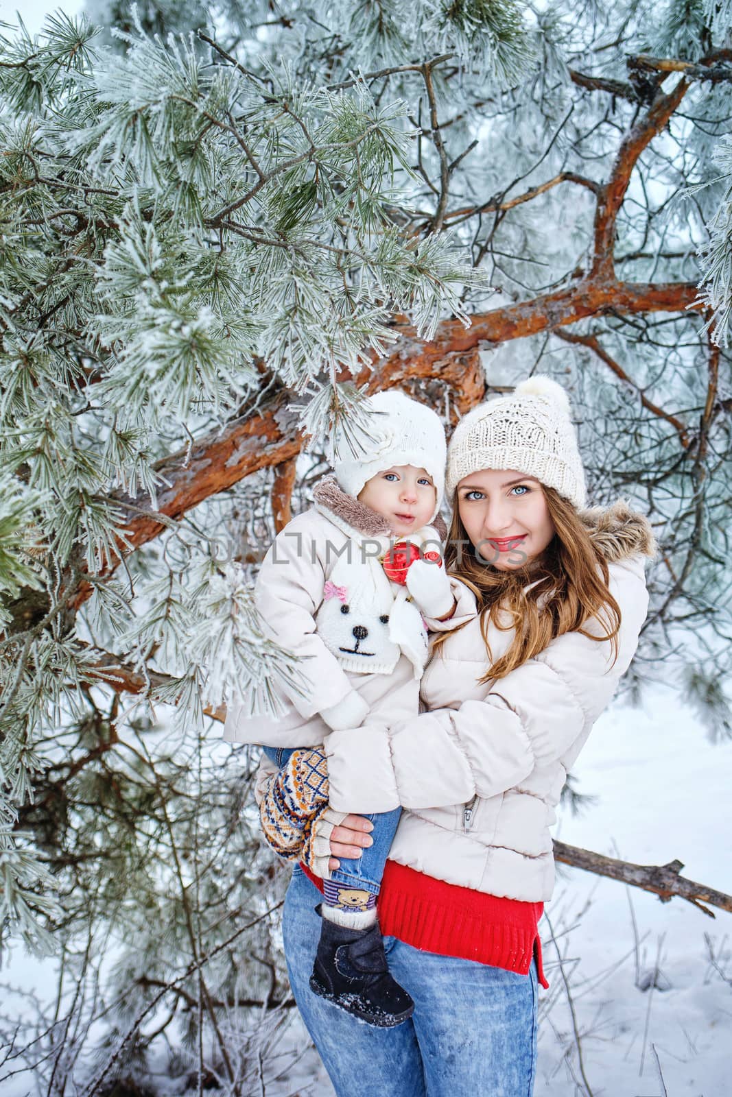 Mother holds daughter in her arms in the winter forest