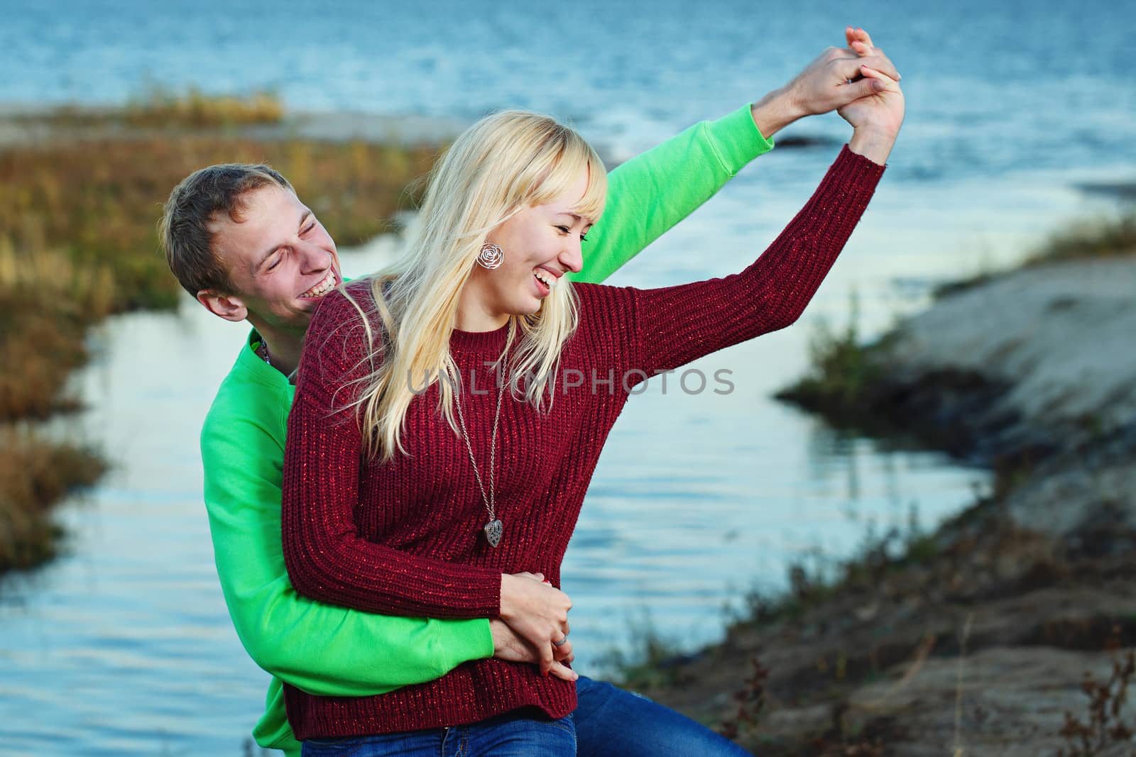Young attractive couple embracing on the riverbank fall day