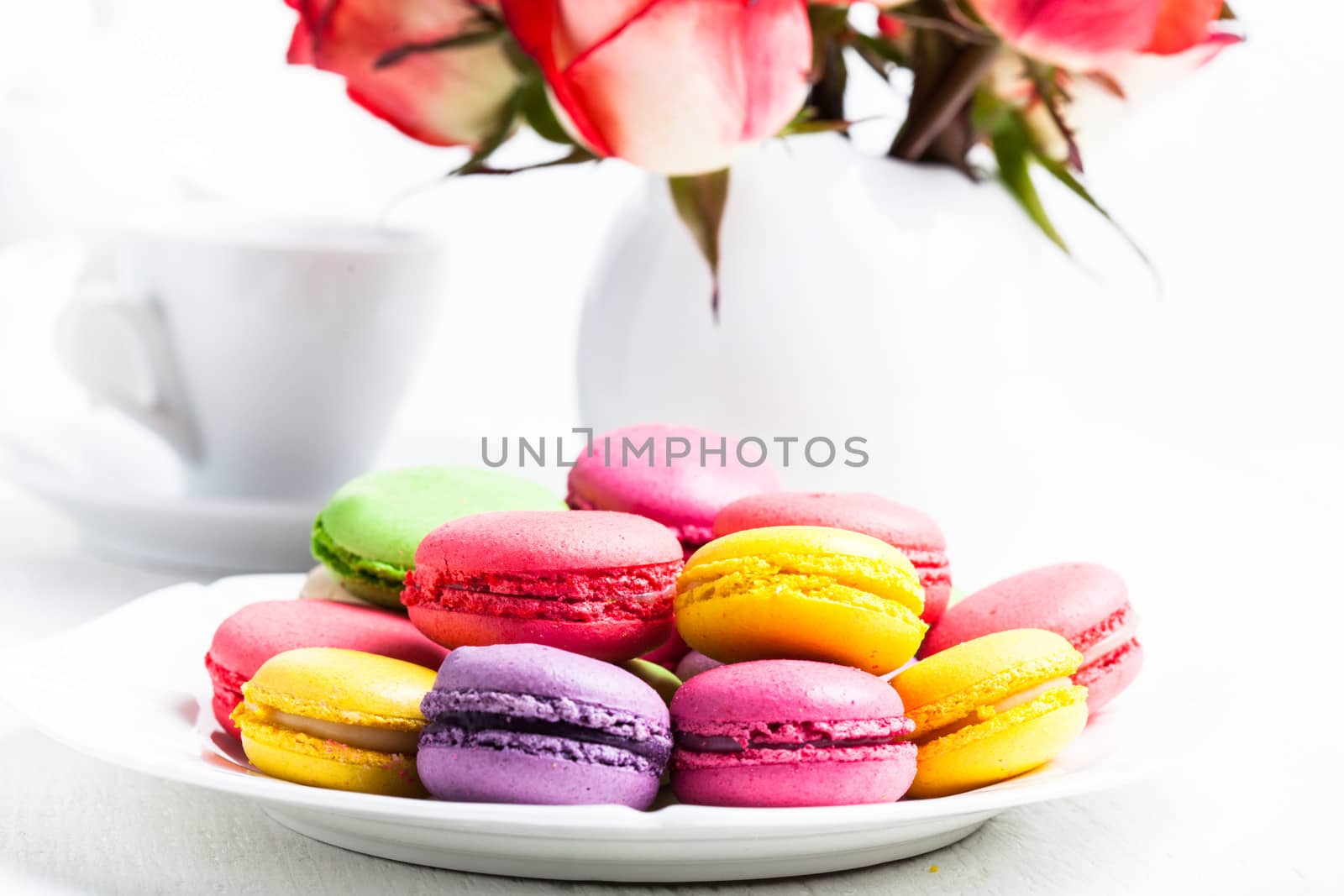 macaroons on the plate and roses in vase. Birthday table