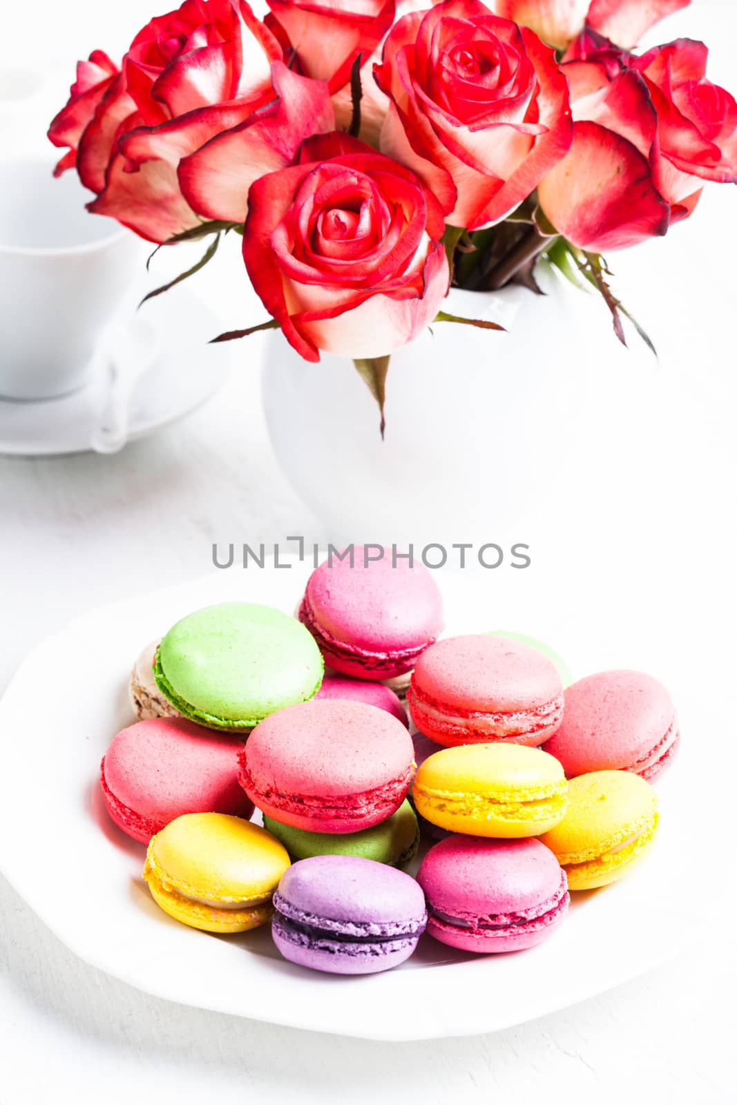 macaroons on the plate and roses in vase. Birthday table