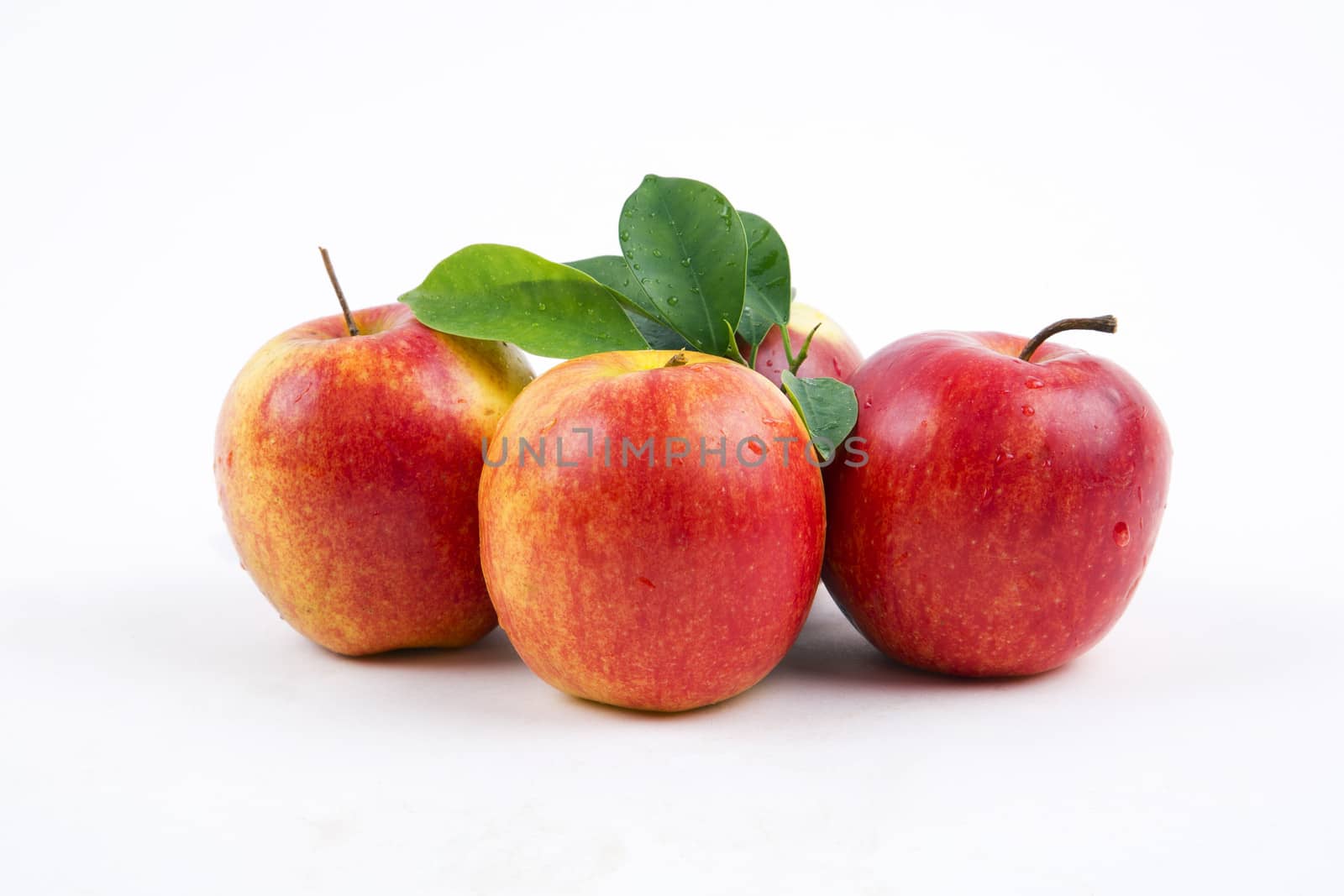 Fresh apples with leaves on a white background.