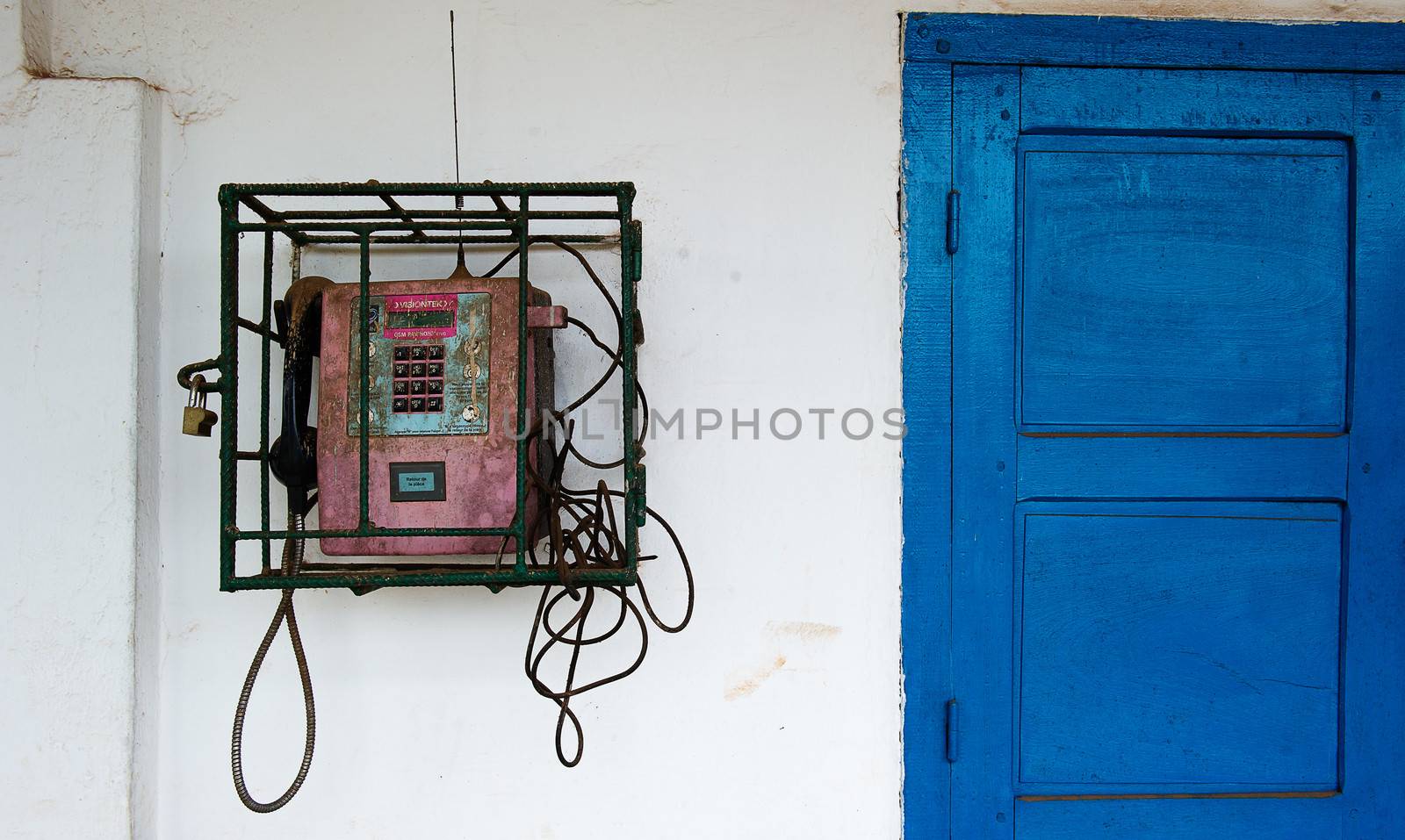 Street phone behind a lattice under the lock. Congo. Africa