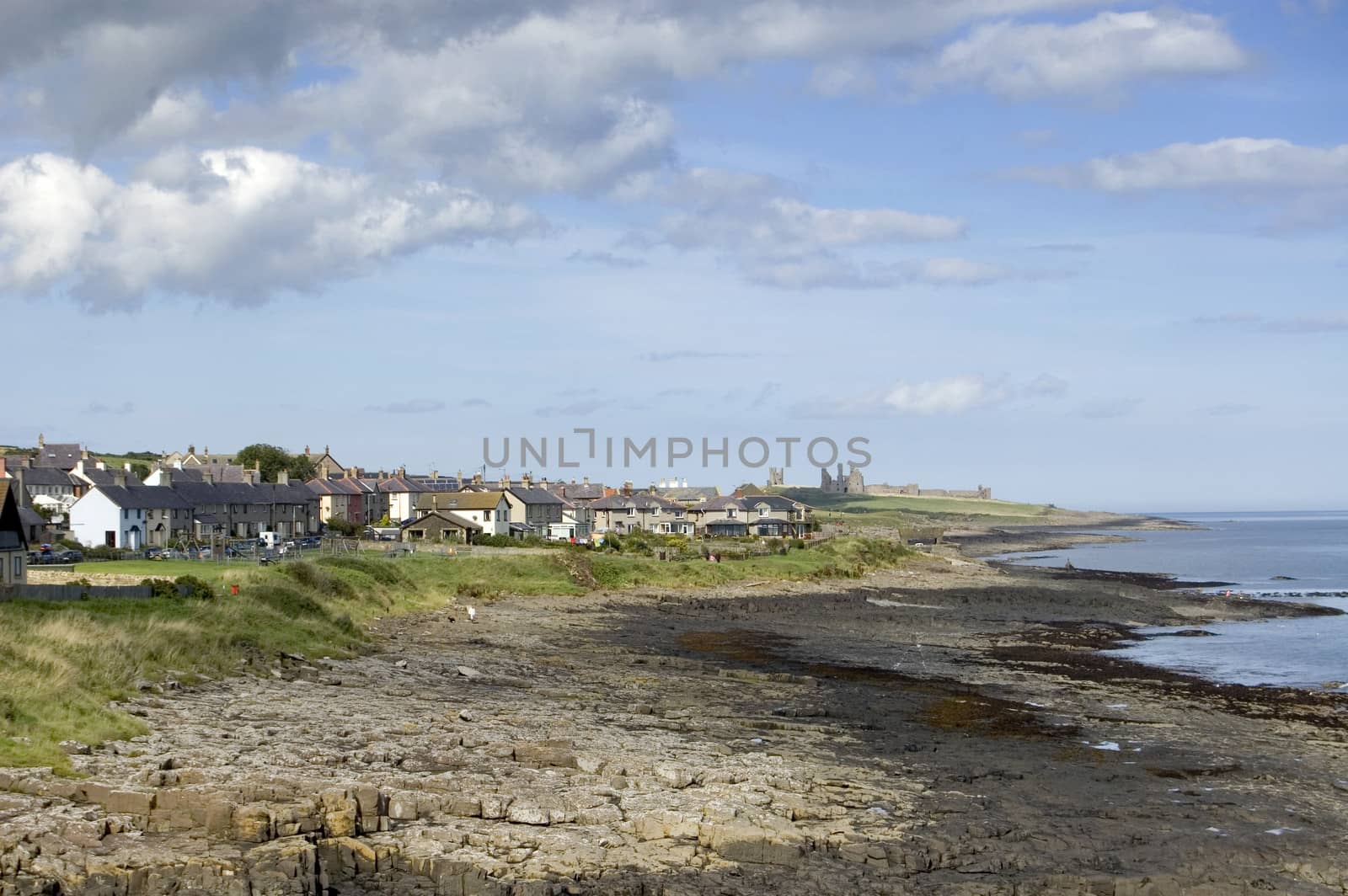 The Northumbrian village of Craster with the ruins of Dunstanburgh Castle in the distance