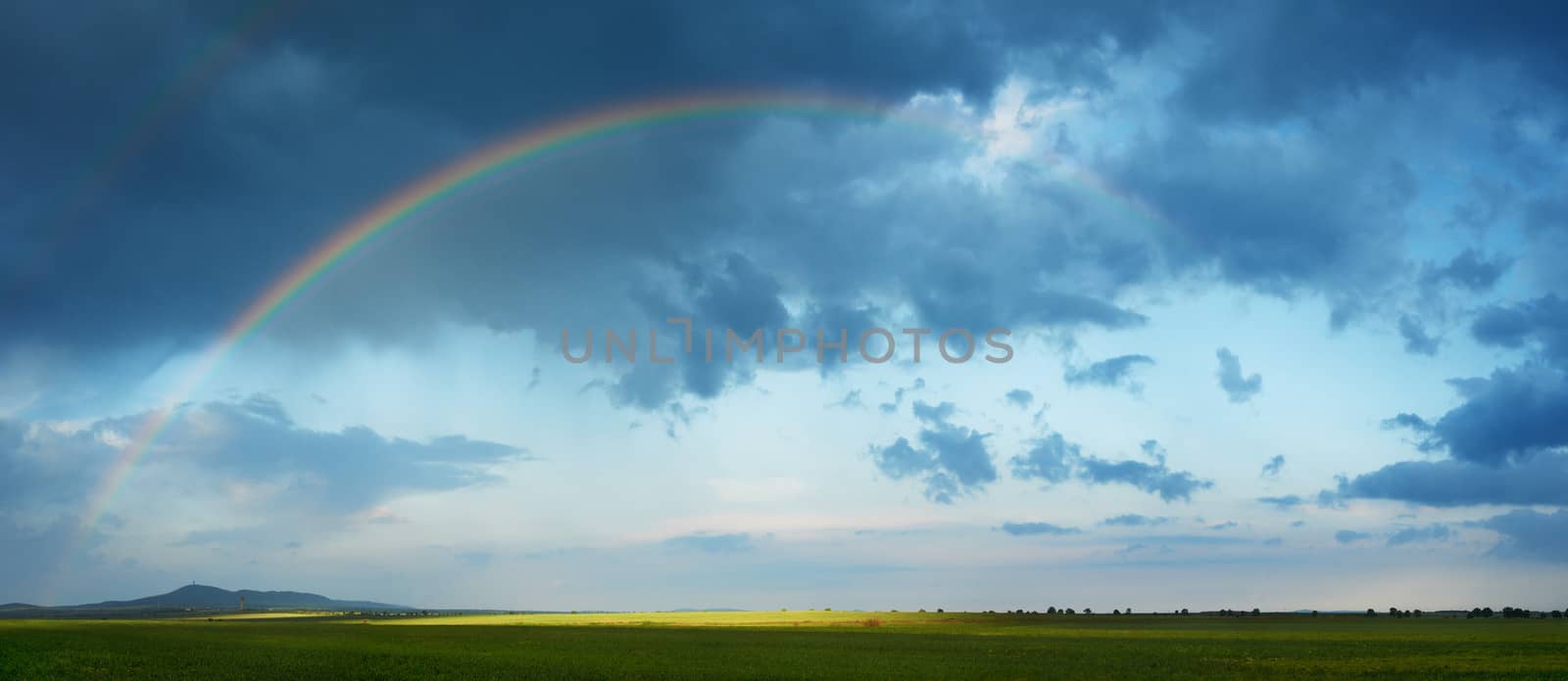 Rainbow arch over green spring field of South Bulgaria