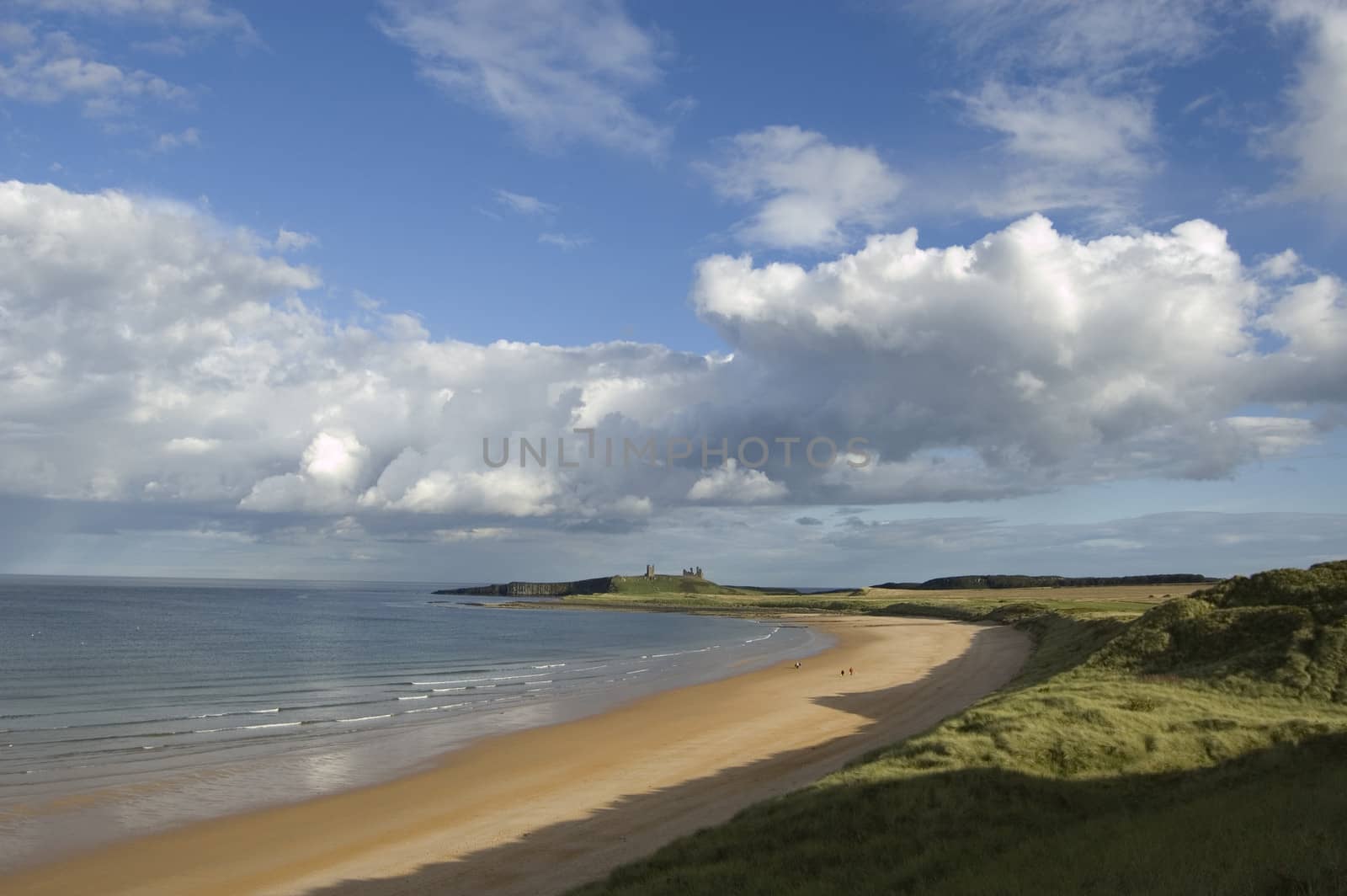 The ruin of Dunstanburgh Castle in the distance beyond the sands of Embleton Bay