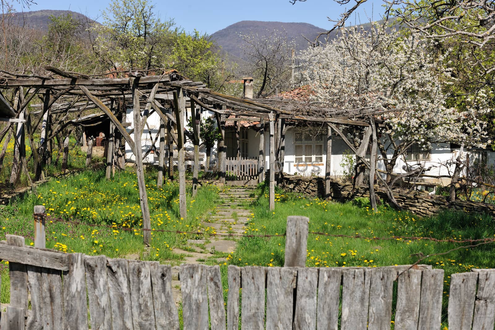 Fence and yard of traditional Bulgarian rural house in spring season