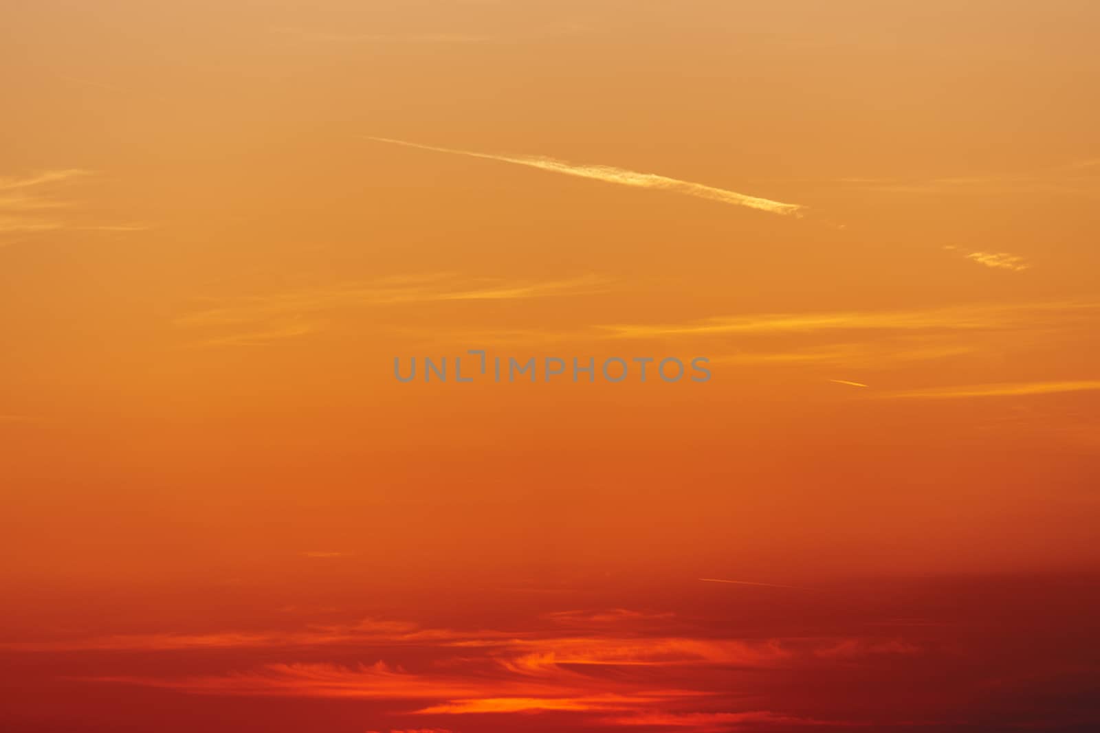 Colorful red sunset sky with plane traces