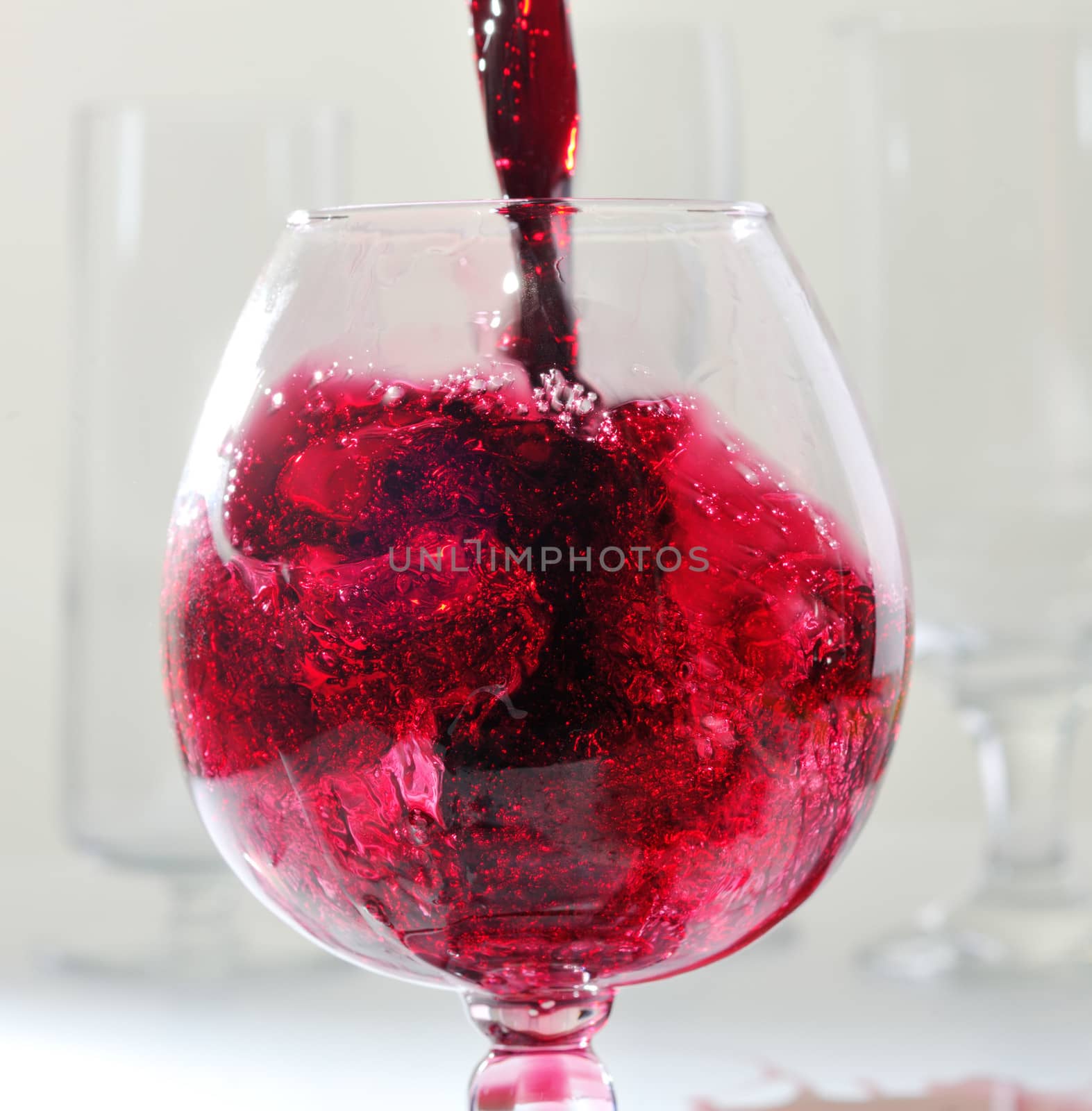 Splashes of red whine while filling a glass by ecobo