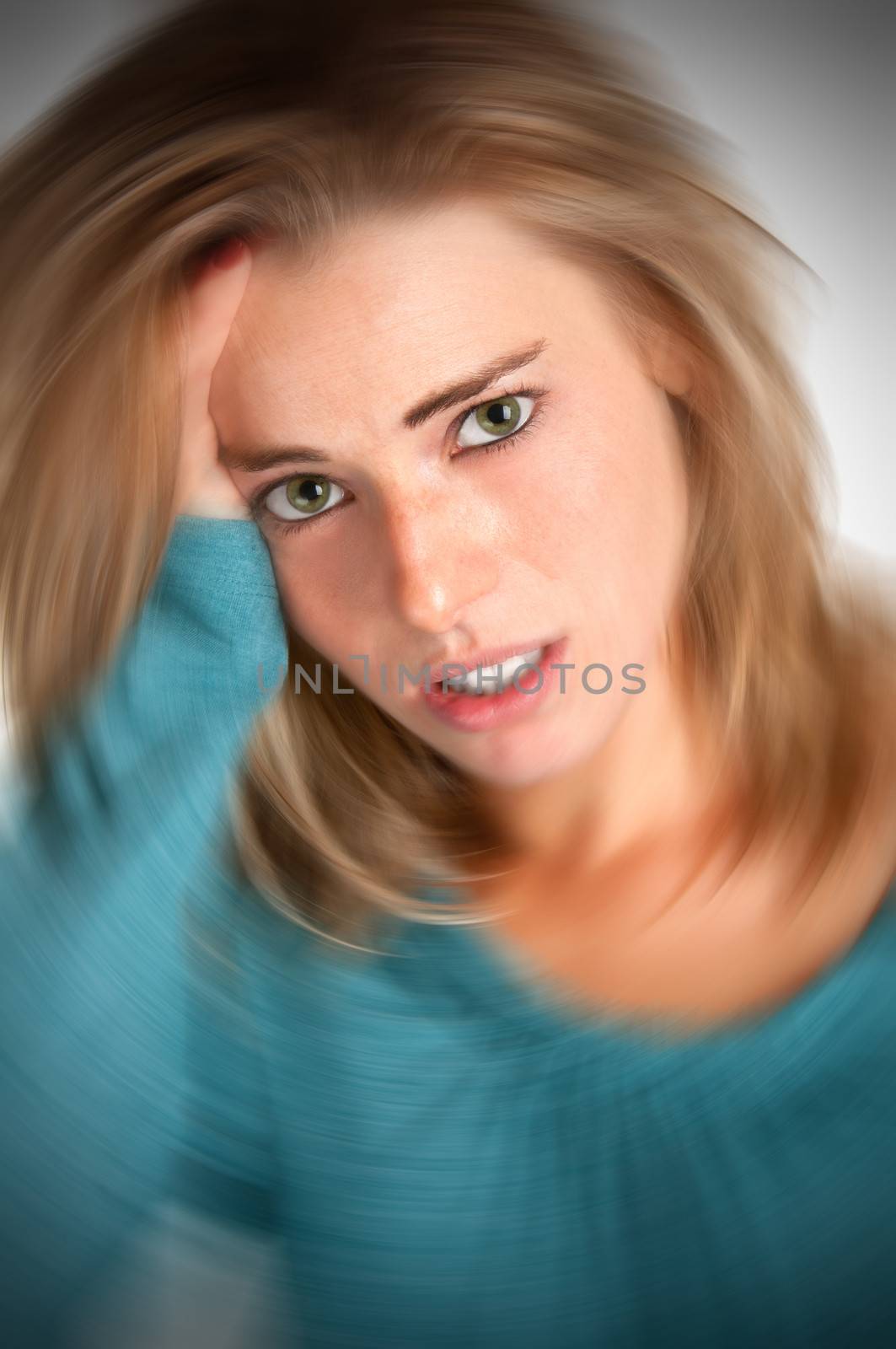 Woman suffering from an headache, holding her hands to the head. Vignetting on the corners, with radial blur effect applied