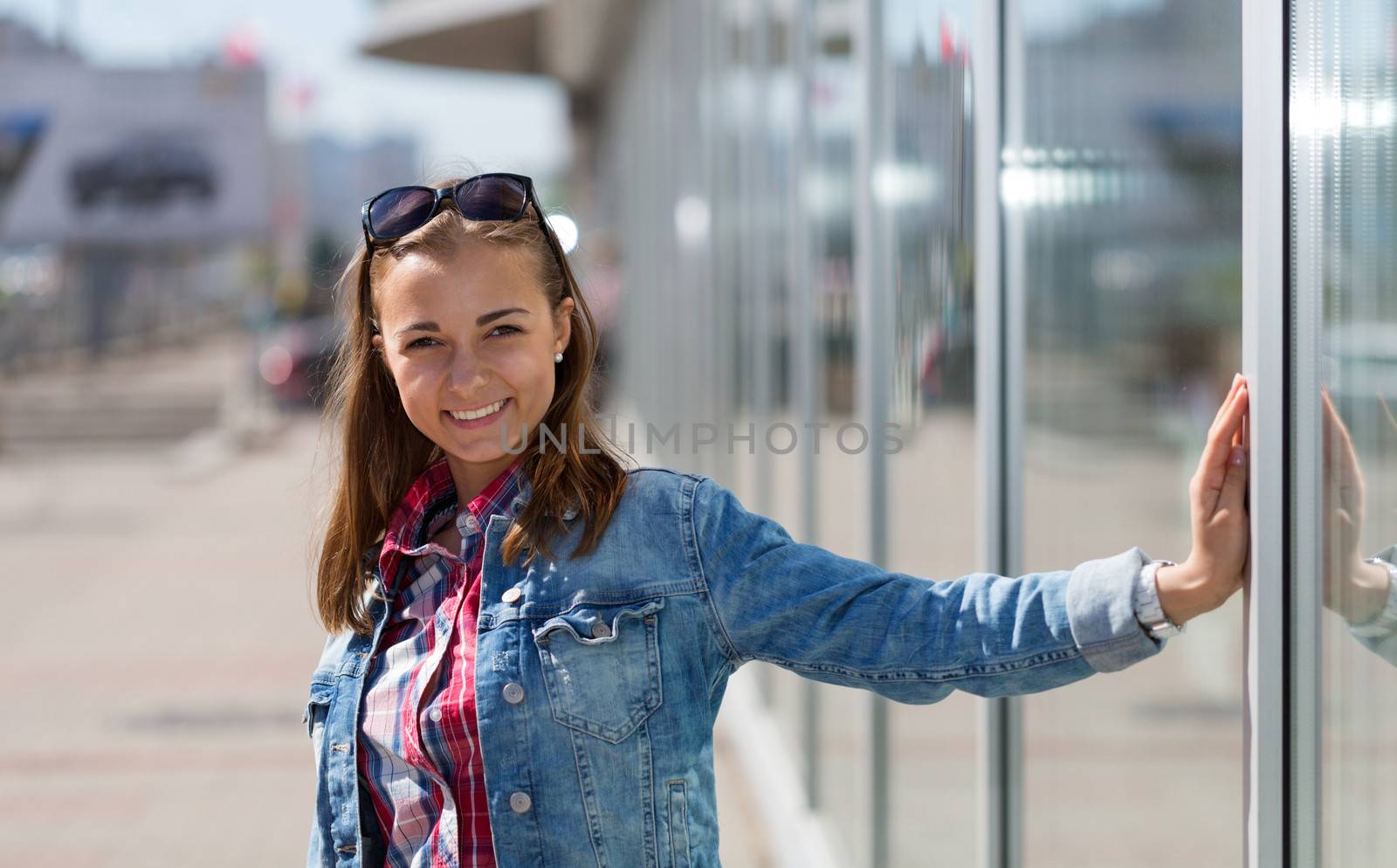 Portrait of a beautiful young girl on the street, squinting in the bright sun.