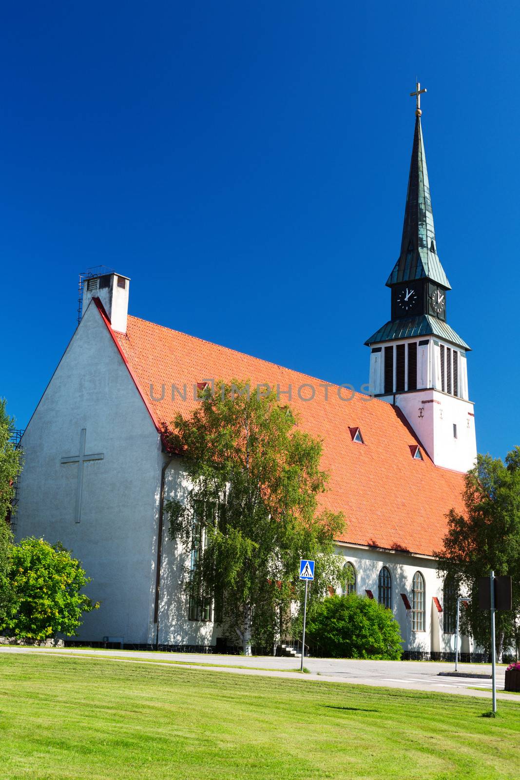 A white rural church stands against a cloudy blue sky.