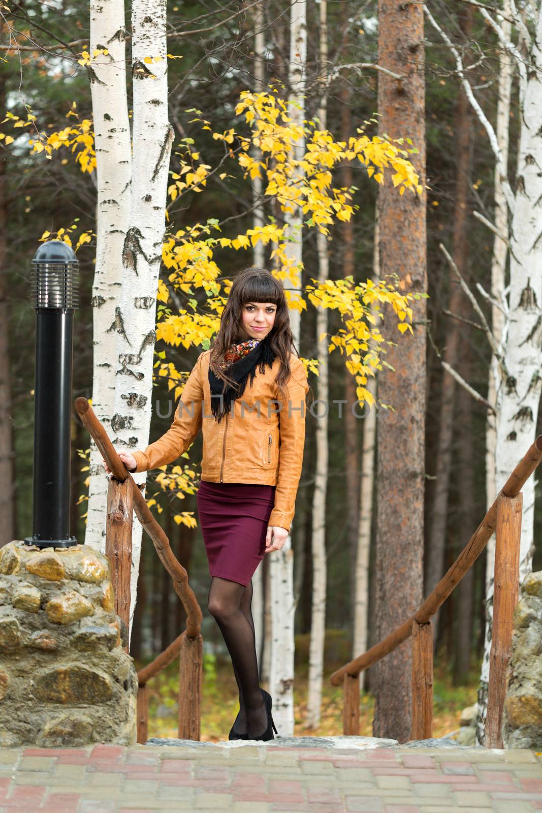 Charming girl in the autumn forest on the stairs