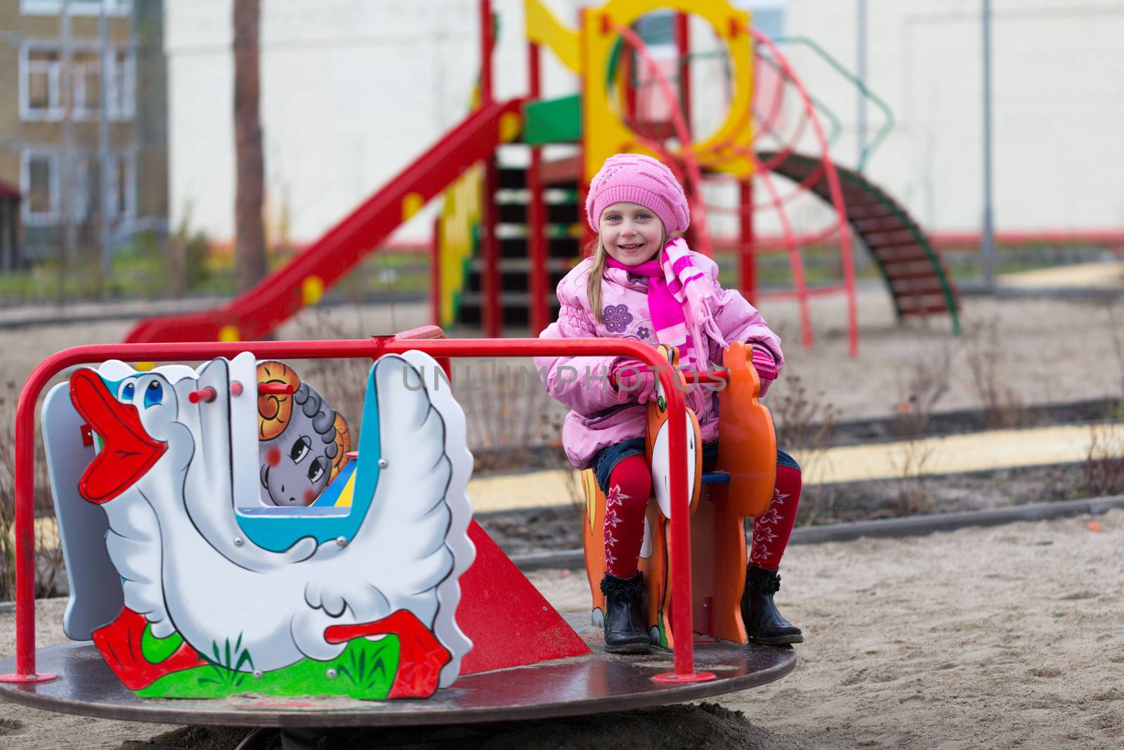 Little girl on the carousel in the autumn clothes