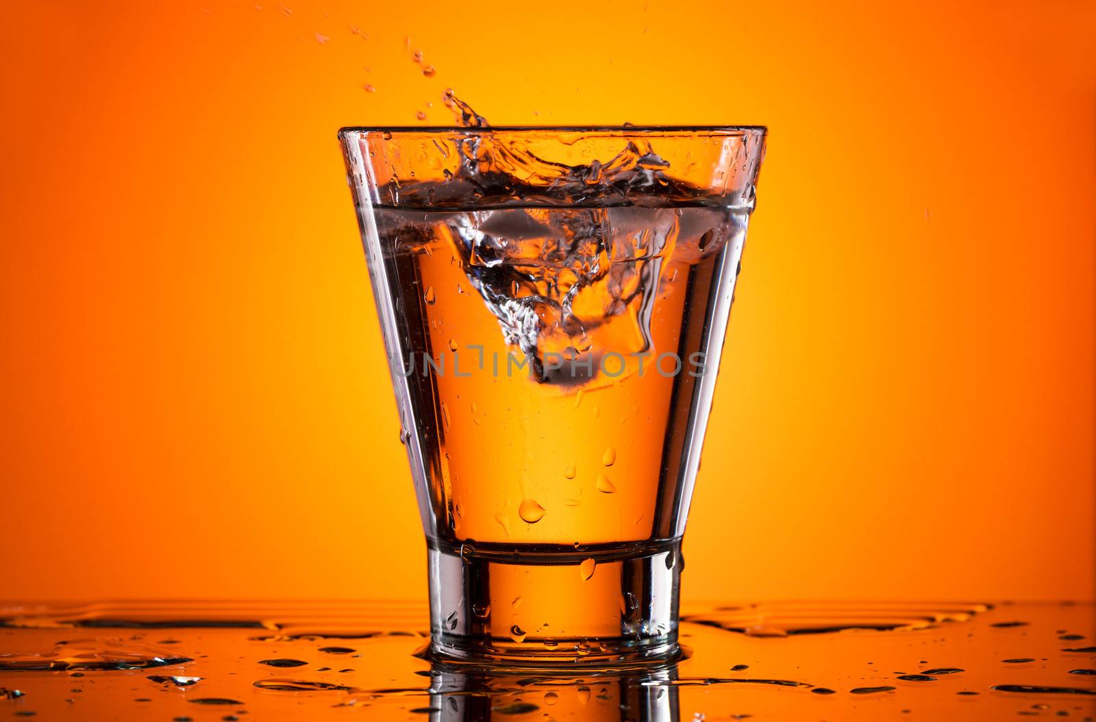 Ice in a glass of water. Orange background