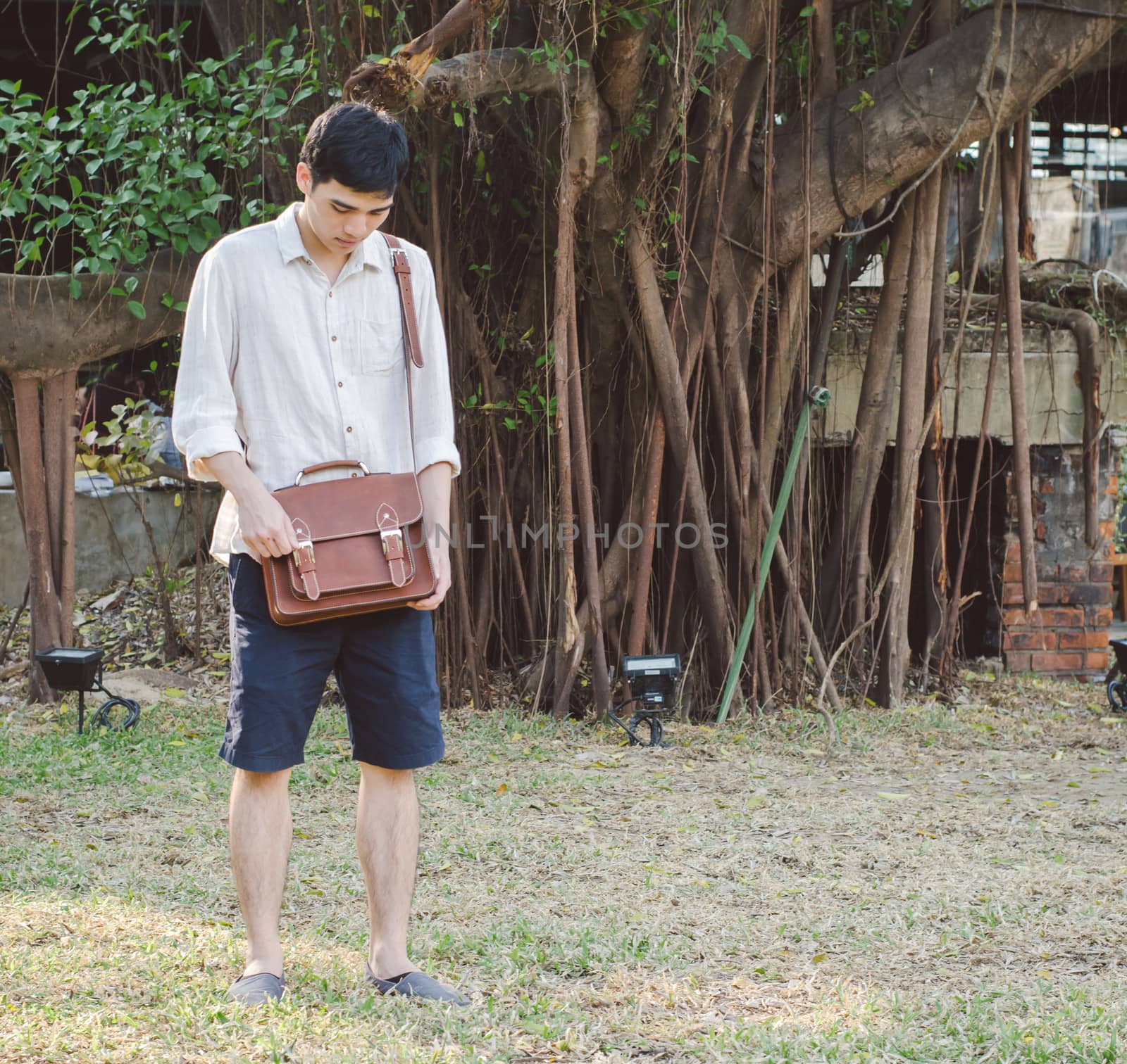 Fashionable young man with leather bag by siraanamwong