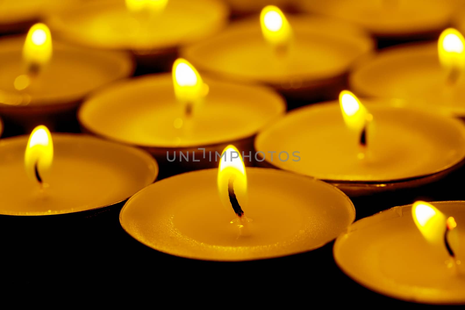 Tea lights candles with fire on dark background