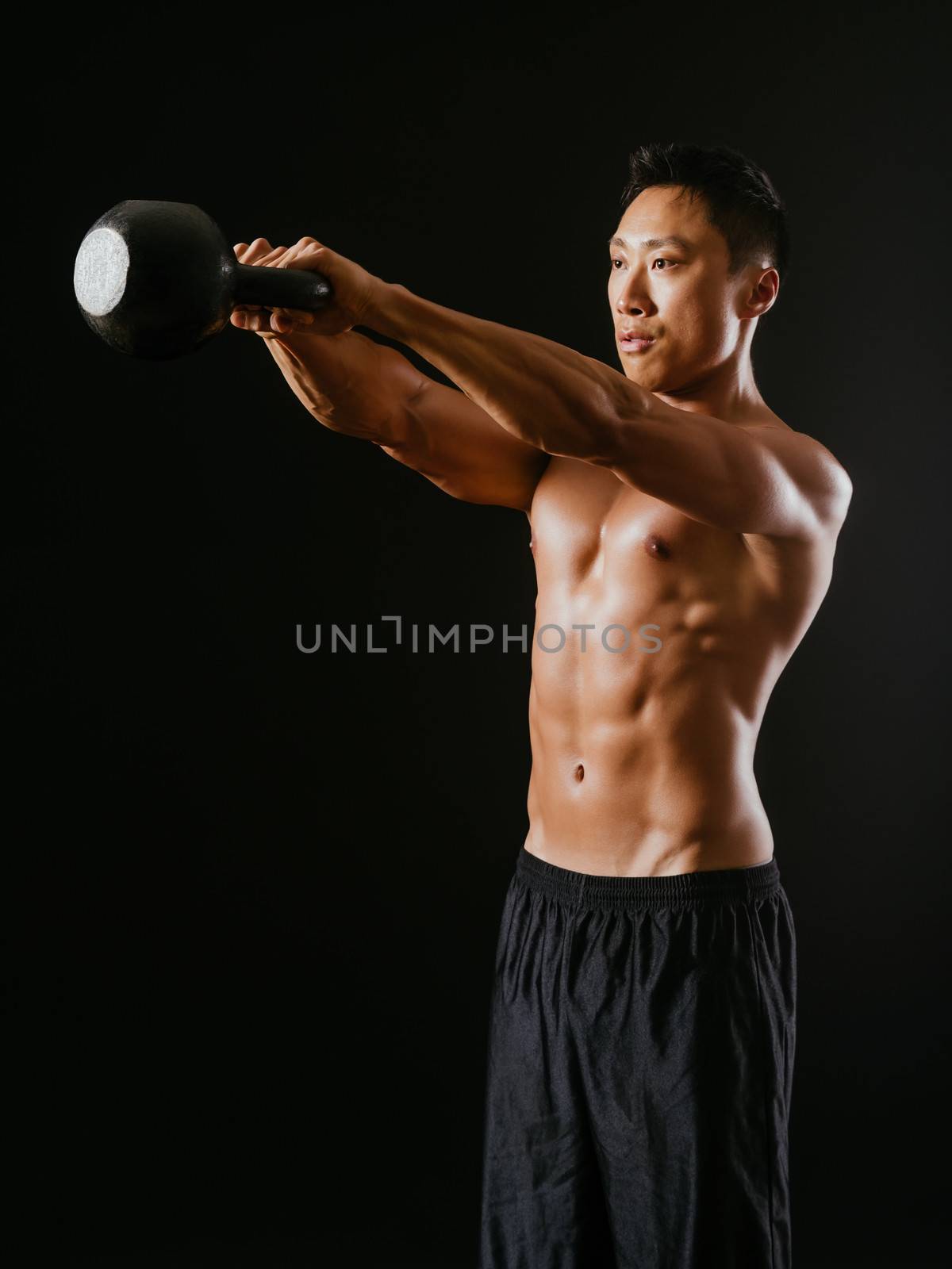 Muscular man working out with kettle bell by sumners